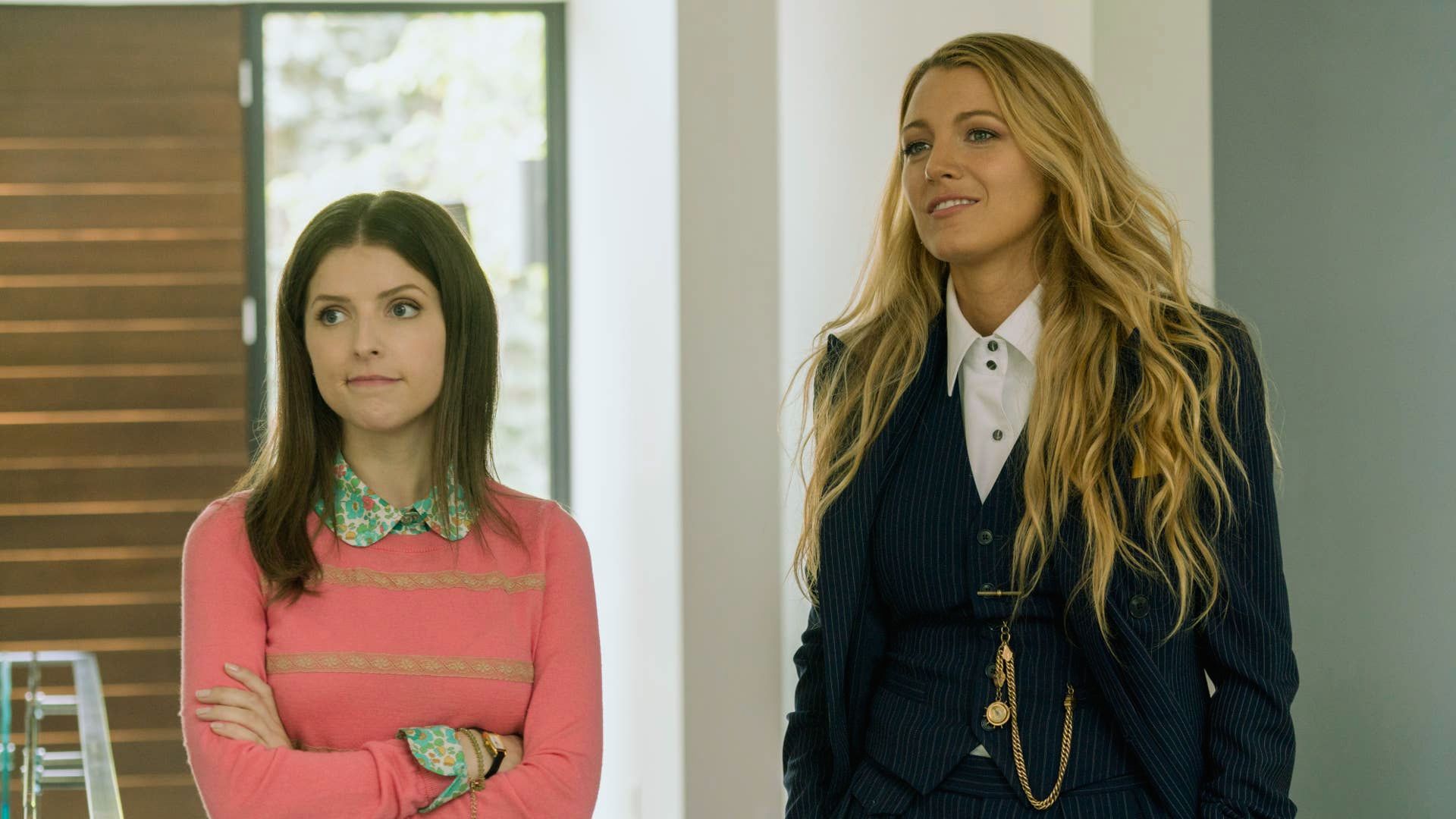 "Two women in professional suits standing side by side, smiling confidently at the camera."