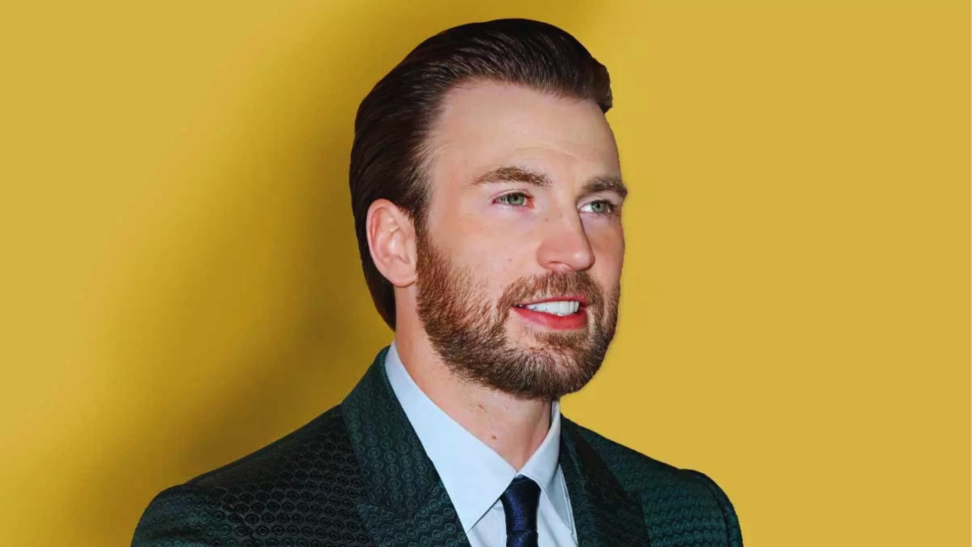 Chris Evans with classic slicked-back pompadour haircut, tapered sides, and groomed beard wearing patterned green suit and tie.