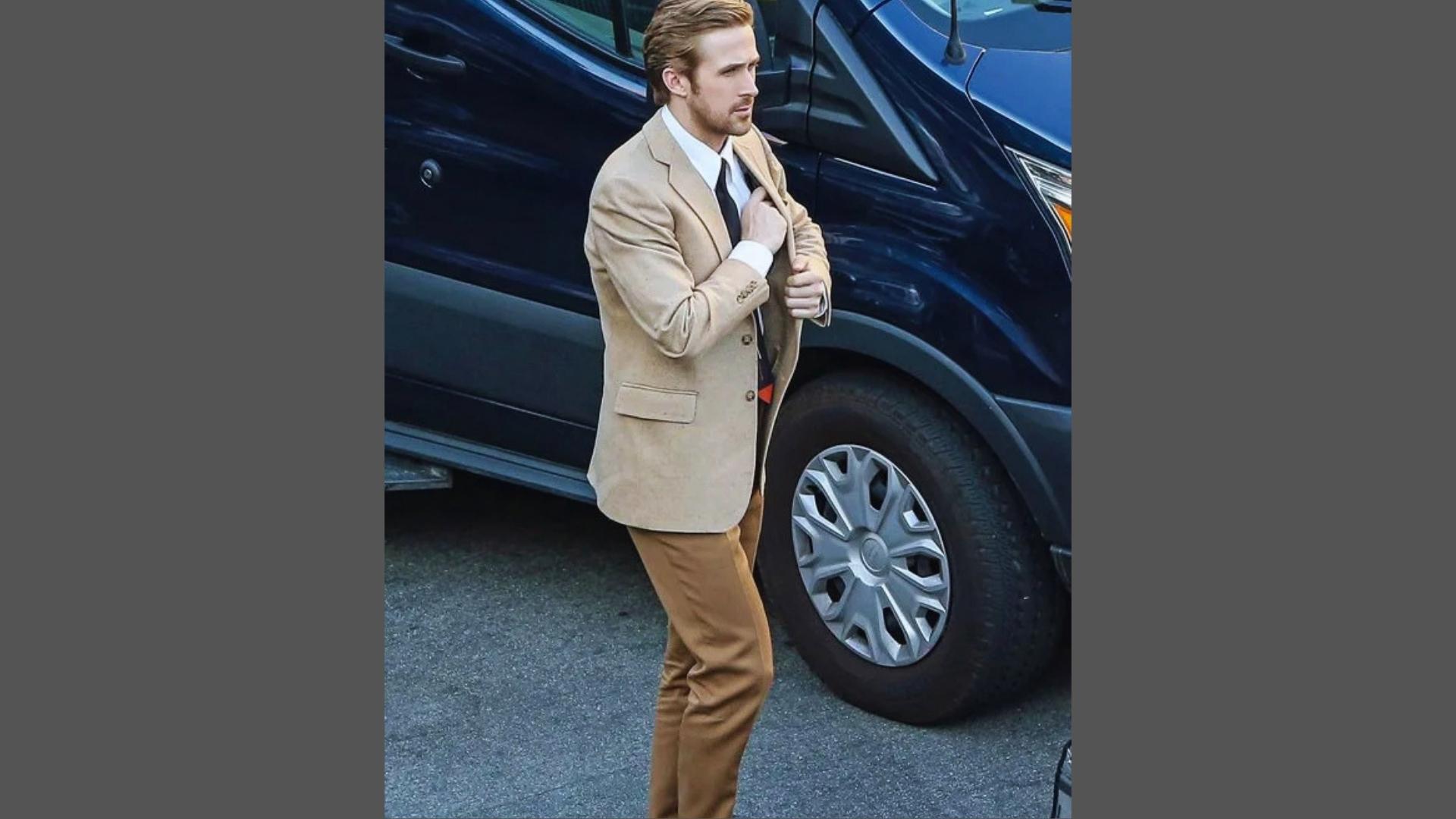 Ryan Gosling in La La Land wearing tan blazer, white shirt, black tie with red detail, and brown trousers by vehicle