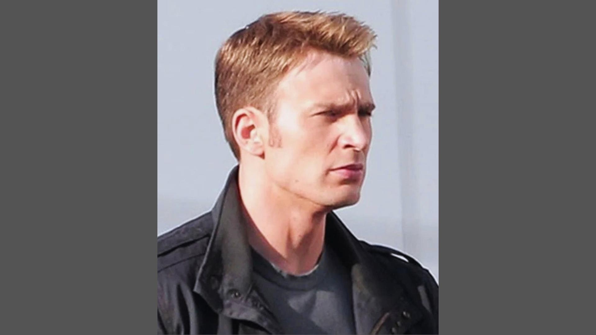 Chris Evans with medium textured crew cut haircut featuring brushed-up front and tight tapered sides wearing black jacket.