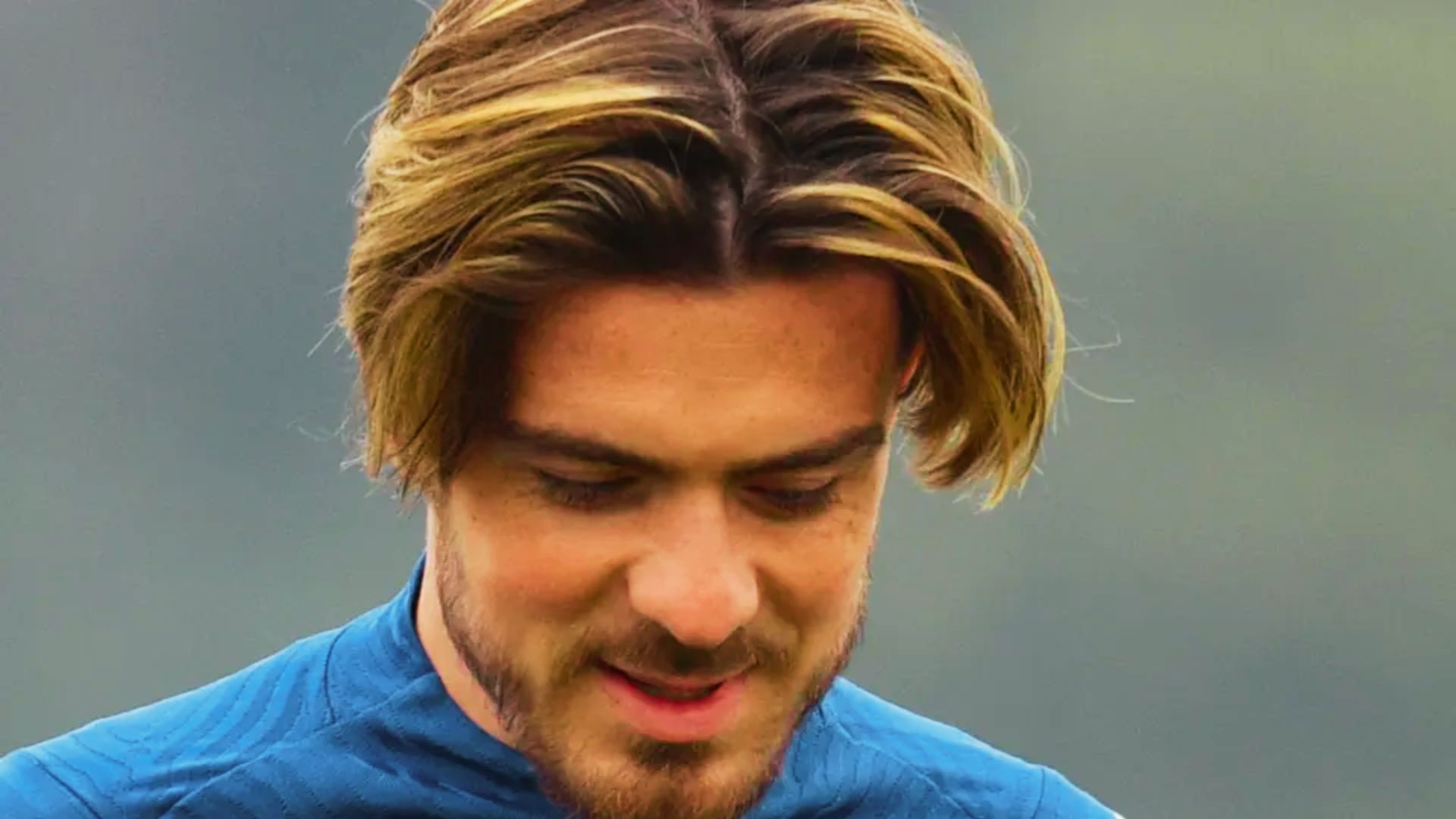 Jack Grealish with long hair gazes intently.