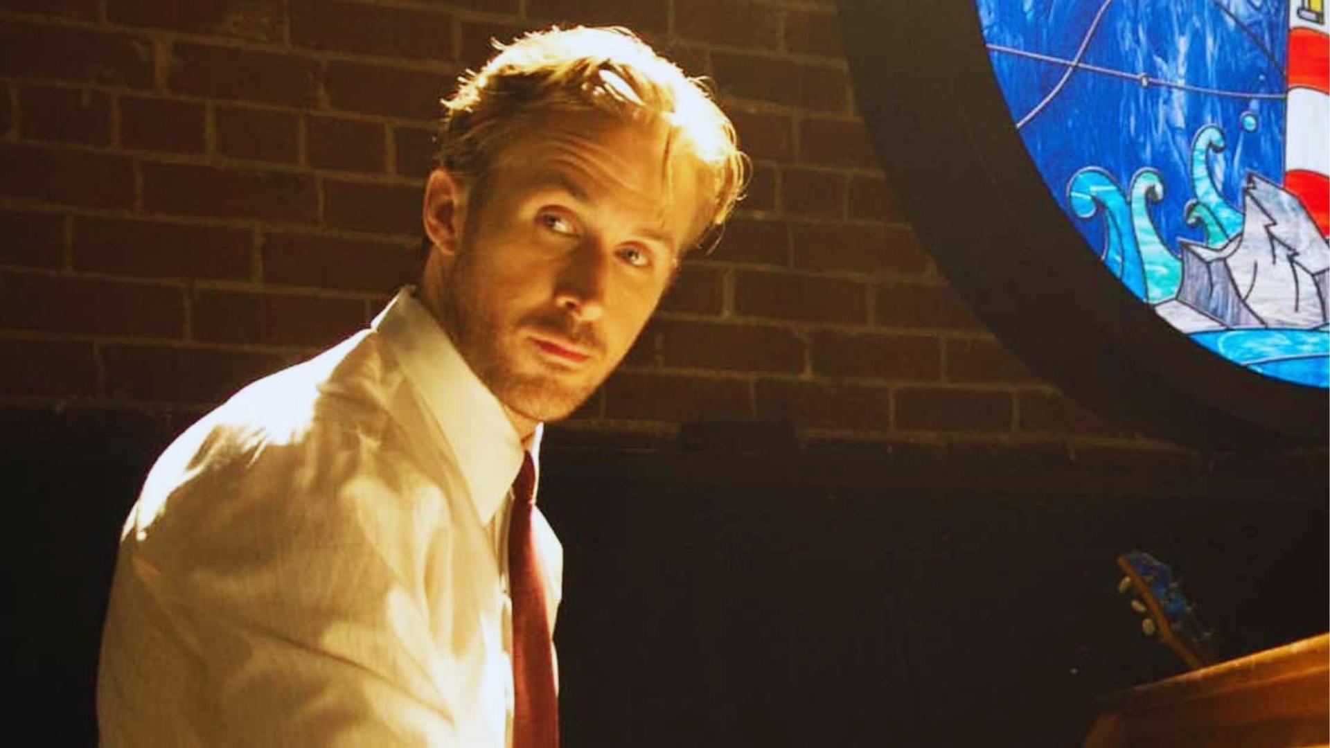 Ryan Gosling as Sebastian in white dress shirt and red tie seated at piano beside stained glass in La La Land