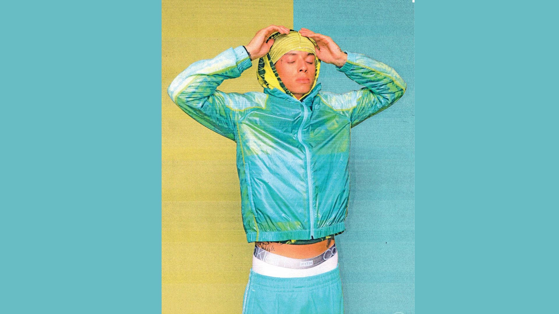 "A man wearing a blue and yellow jacket stands confidently, presenting a casual and stylish appearance."