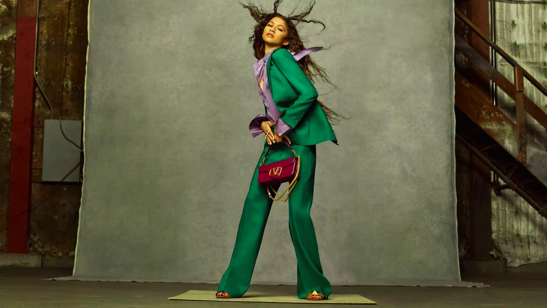 Zendaya strikes a dynamic pose in a vibrant emerald suit with a lilac silk blouse and bold Valentino bag.
