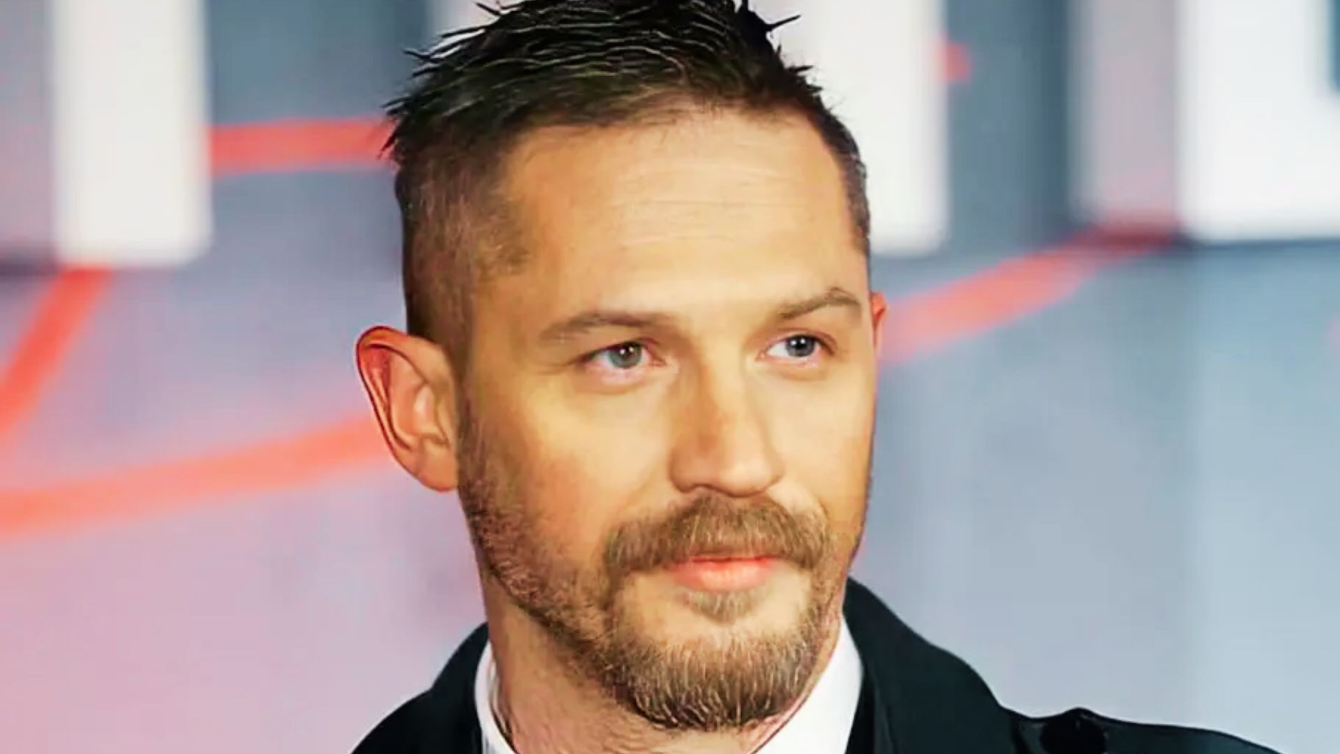 Tom Hardy at a red carpet event with a short, spiky textured top and sharply faded sides.