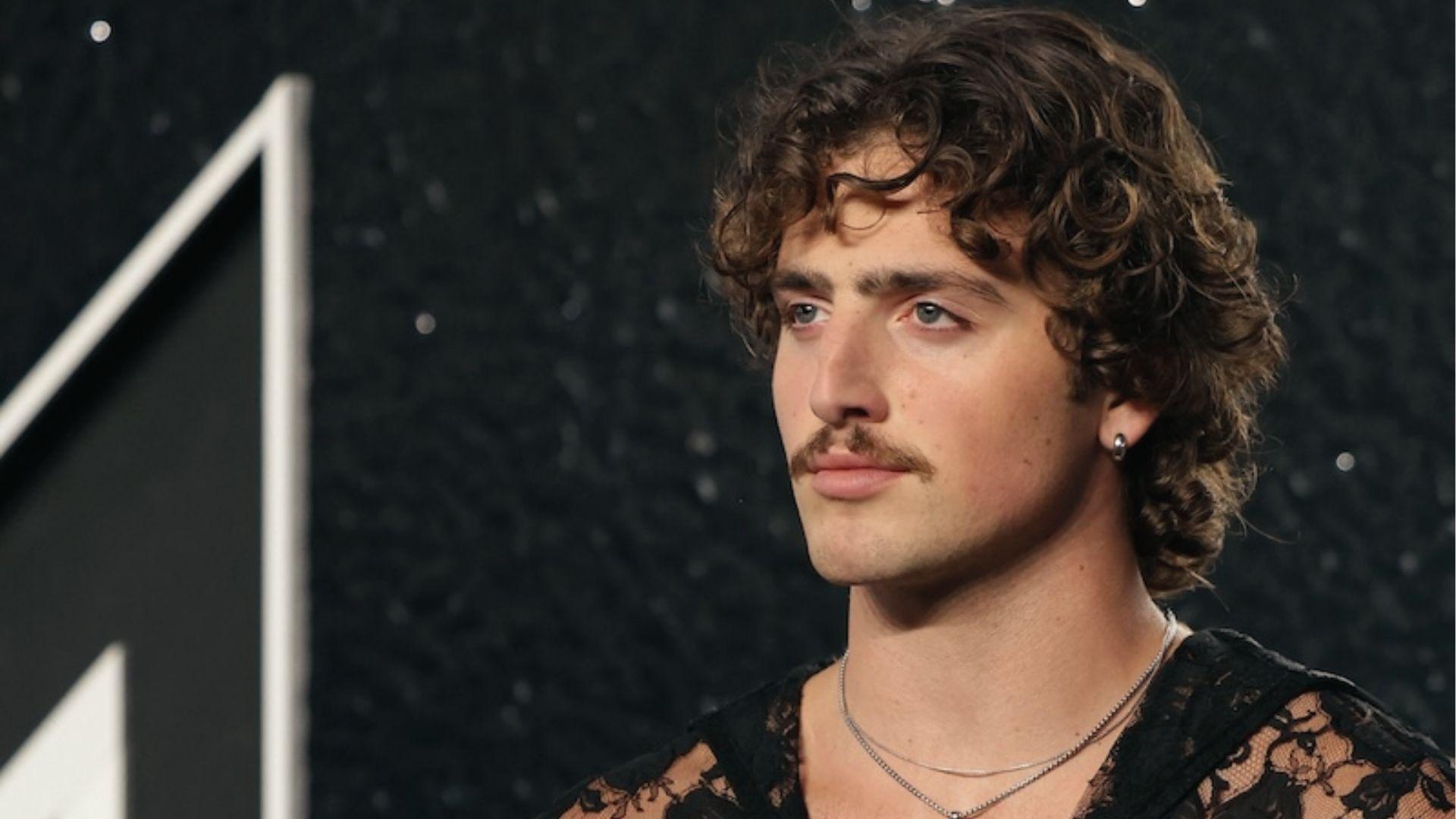 Benson Boone in black lace shows textured curly bob with soft forehead curls.