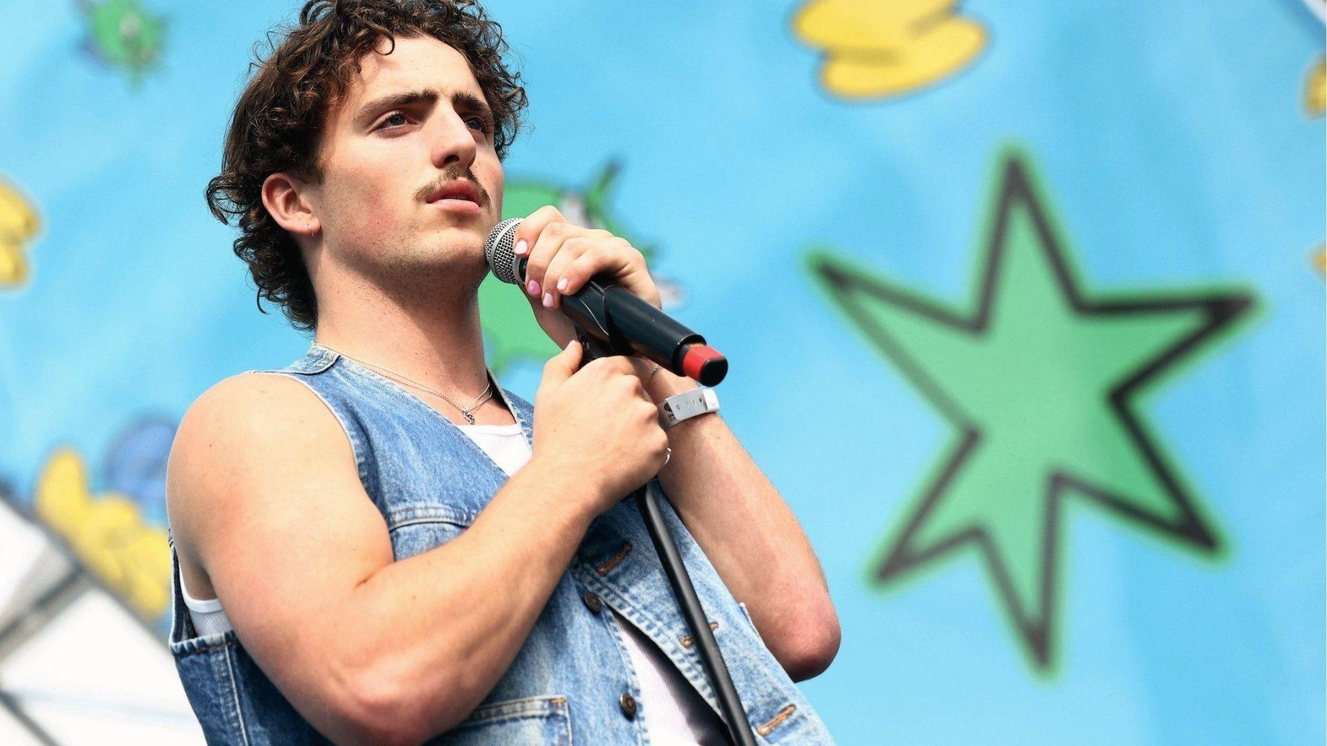 Benson Boone performs in a denim vest showing bouncy short curls and natural volume.