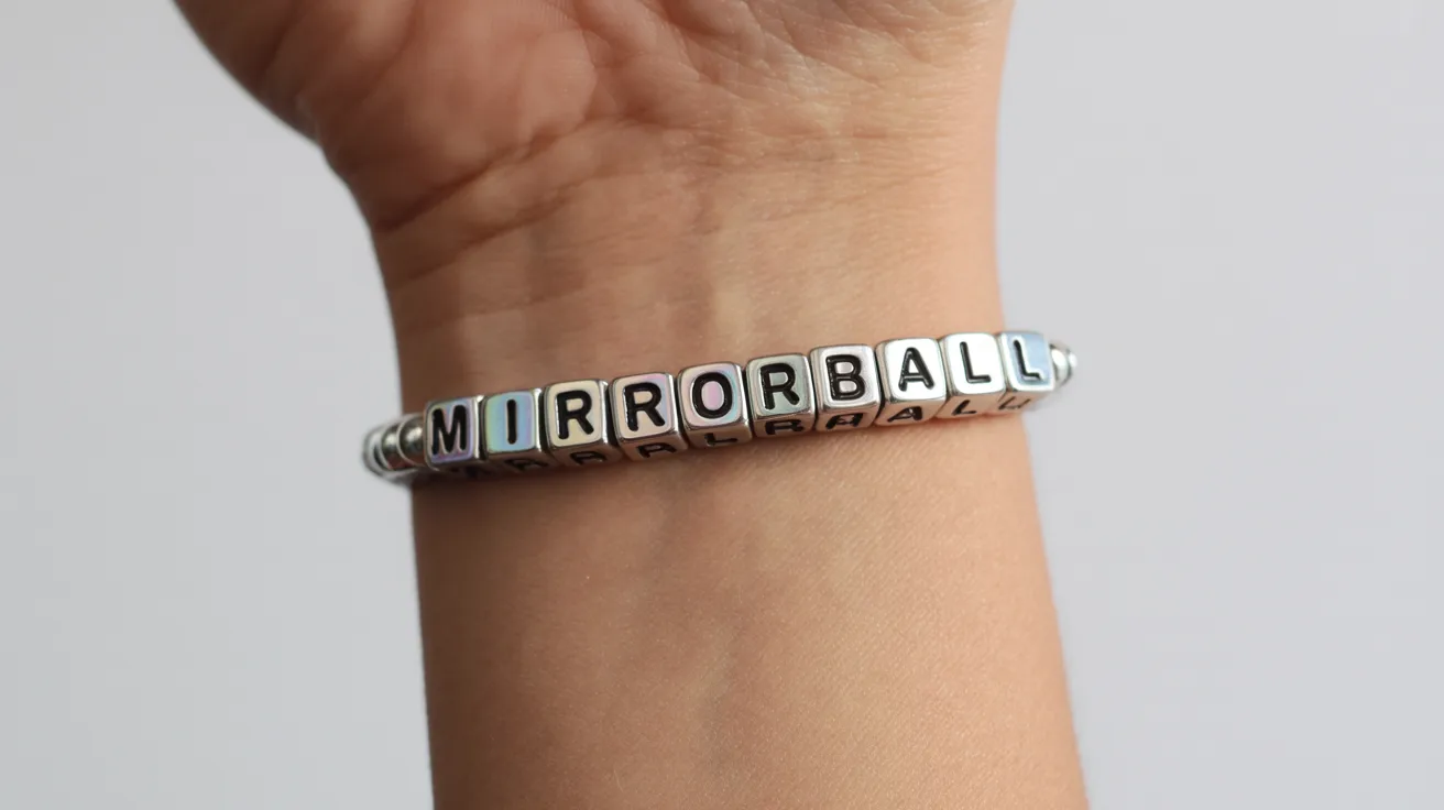 wrist close-up with silver iridescent bracelet featuring cube beads spelling MIRRORBALL in uppercase clearly.