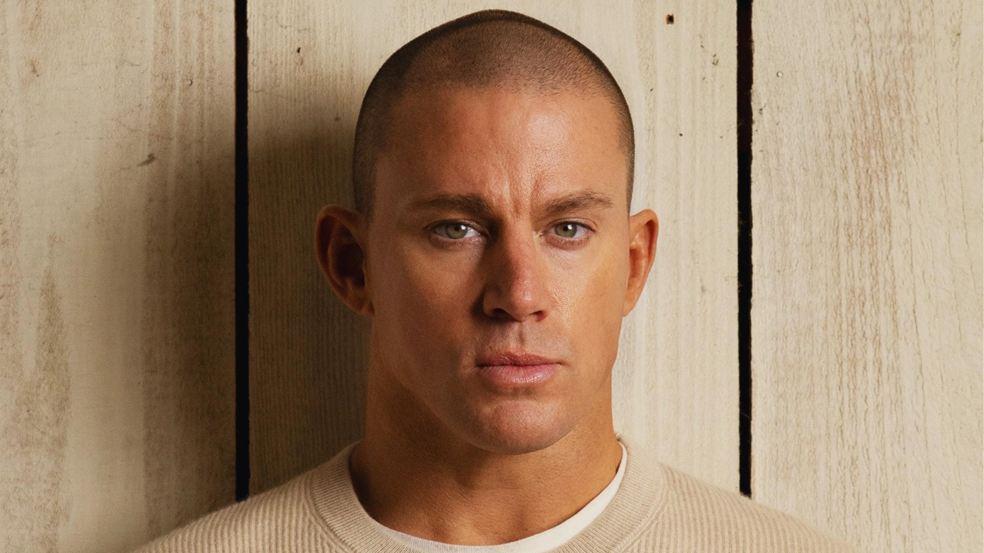 Channing Tatum with an ultra-short induction buzz cut in a beige sweater, a clean minimalist style for sharp jawlines.