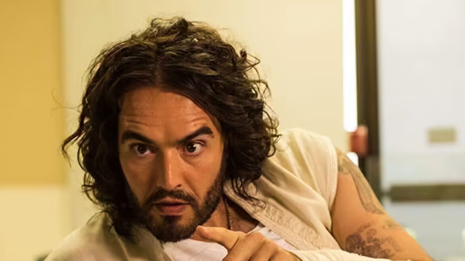 Russell Brand with textured, messy short hair, portraying a character in "The Big Short" film scene.