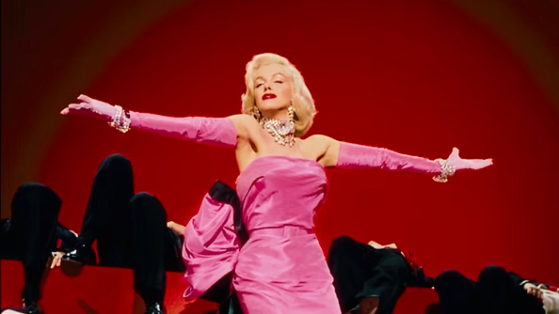 Marilyn Monroe performs in a strapless hot pink satin gown with a dramatic bow and matching opera gloves.