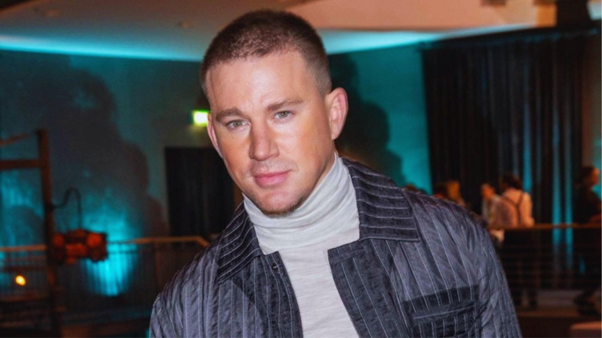 Channing Tatum in a striped jacket with a mid-fade buzz cut and light goatee, a modern textured buzz style.