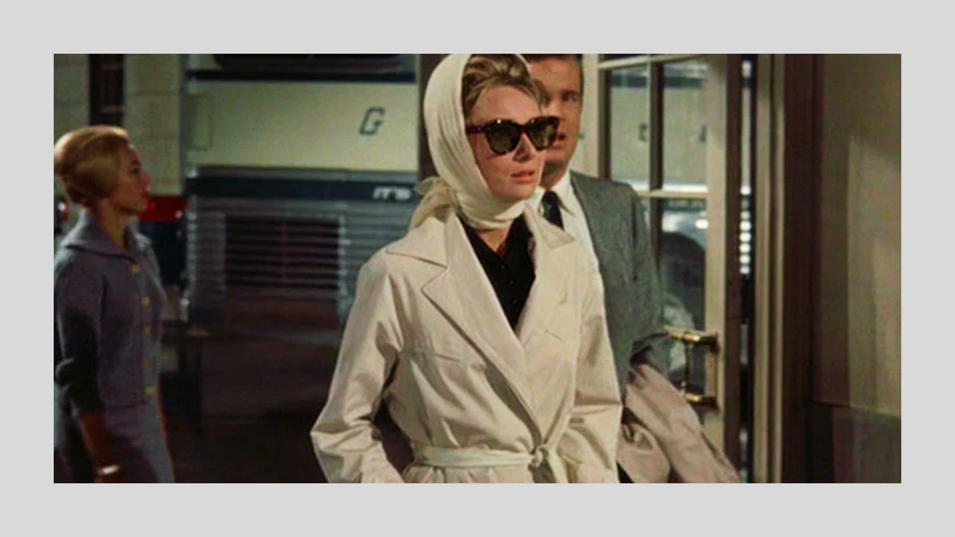 Audrey Hepburn in a belted white trench coat and silk headscarf with oversized sunglasses from Breakfast at Tiffany's.
