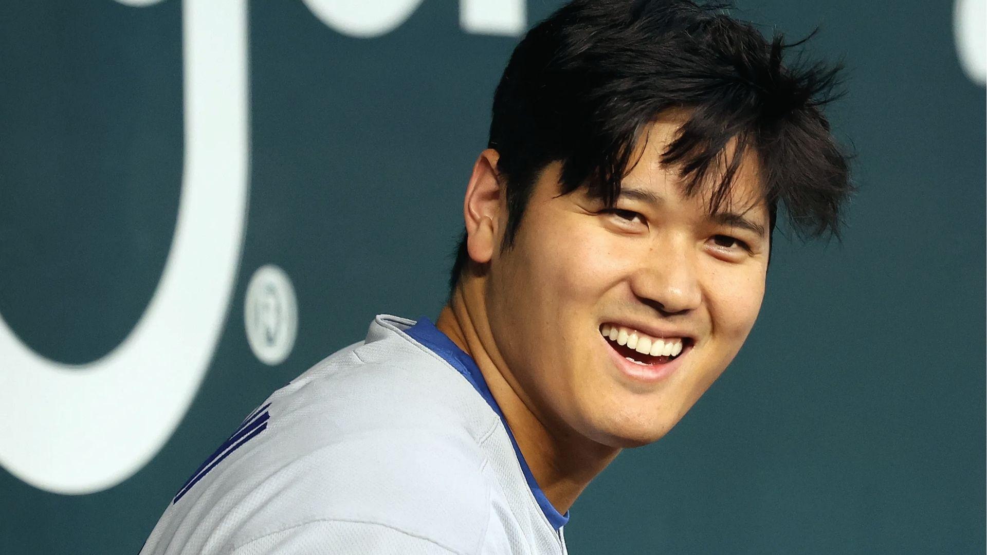Shohei Ohtani smiling in dugout with messy textured haircut and wispy bangs