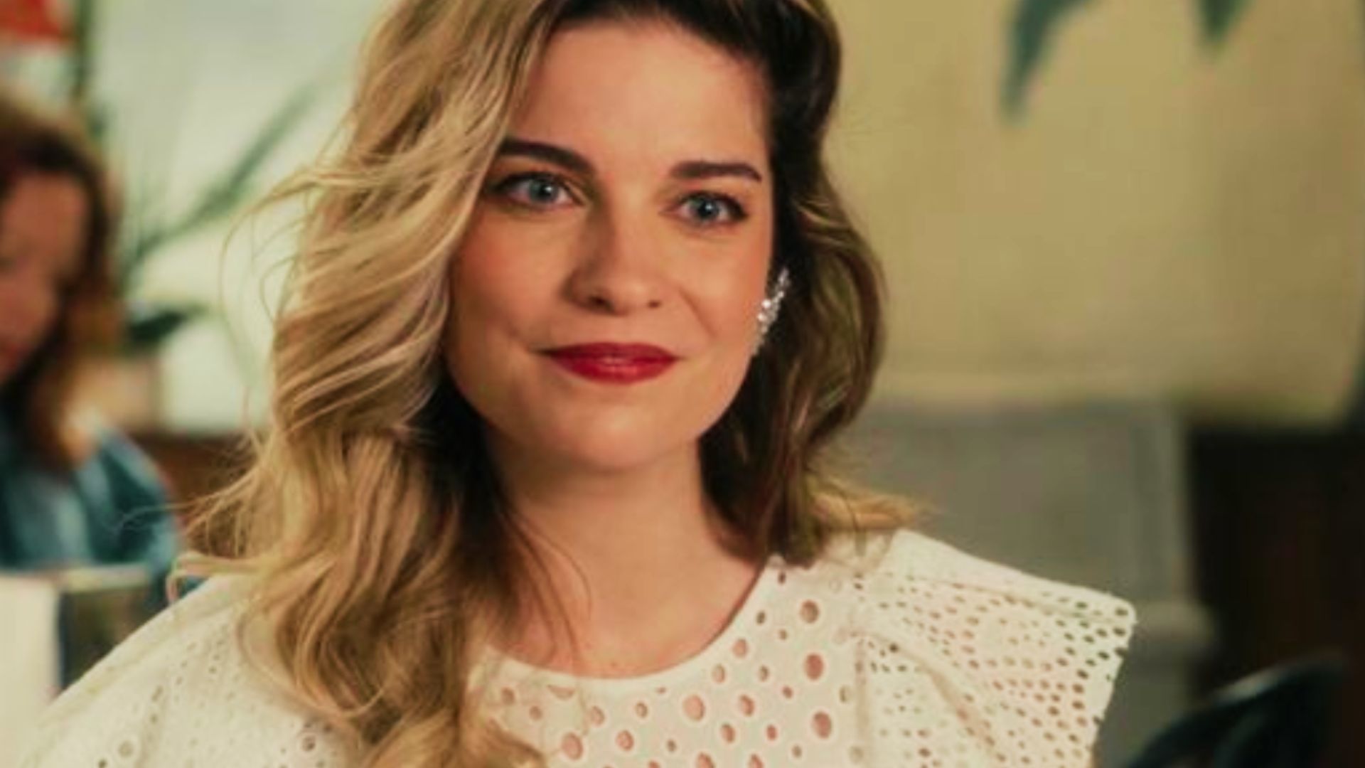 Alexis wears a white eyelet lace top with ruffled shoulders and soft waves.
