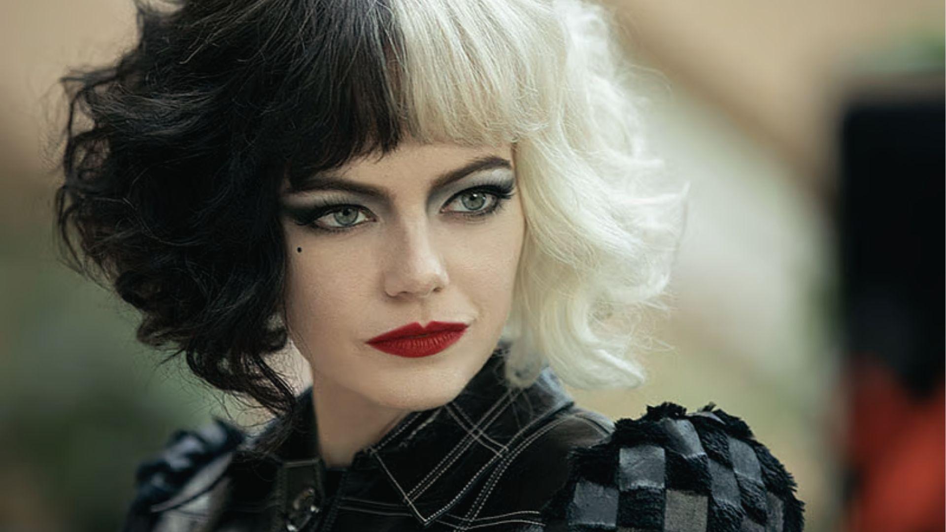 Emma Stone as Cruella with black white hair and punk leather jacket with bold makeup.