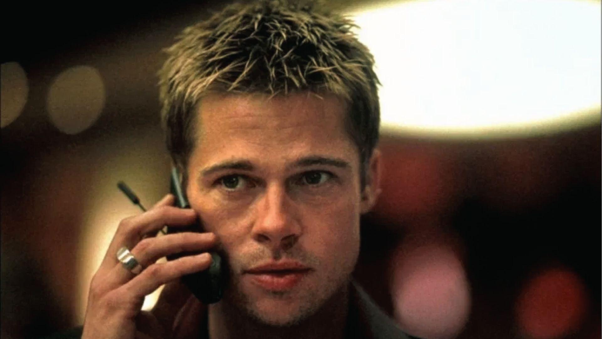 Brad Pitt with spiky blond short-medium hair on phone, wearing ring, dramatic lighting