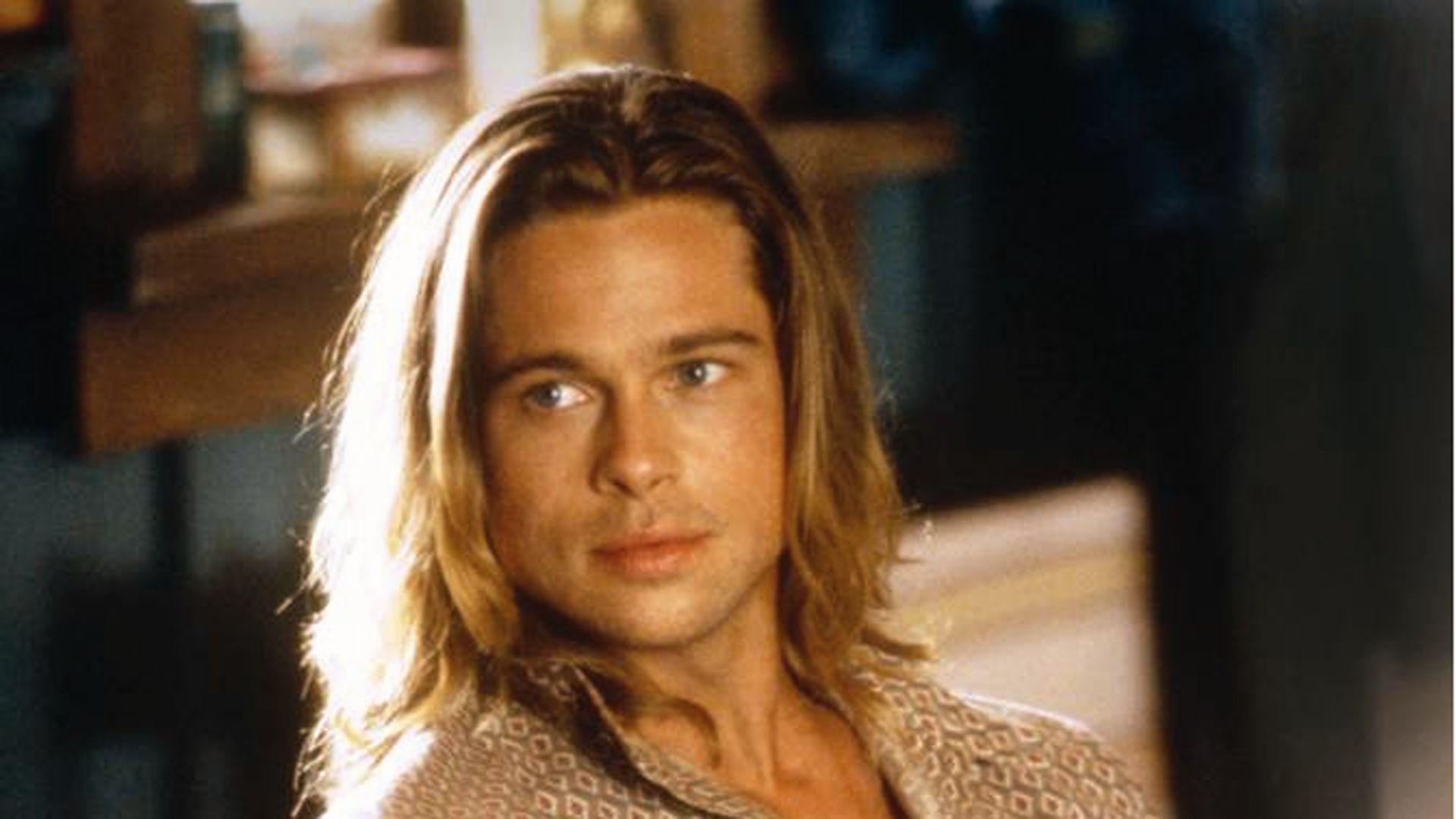 Brad Pitt with long blond hair and patterned shirt, young look, warm indoor light