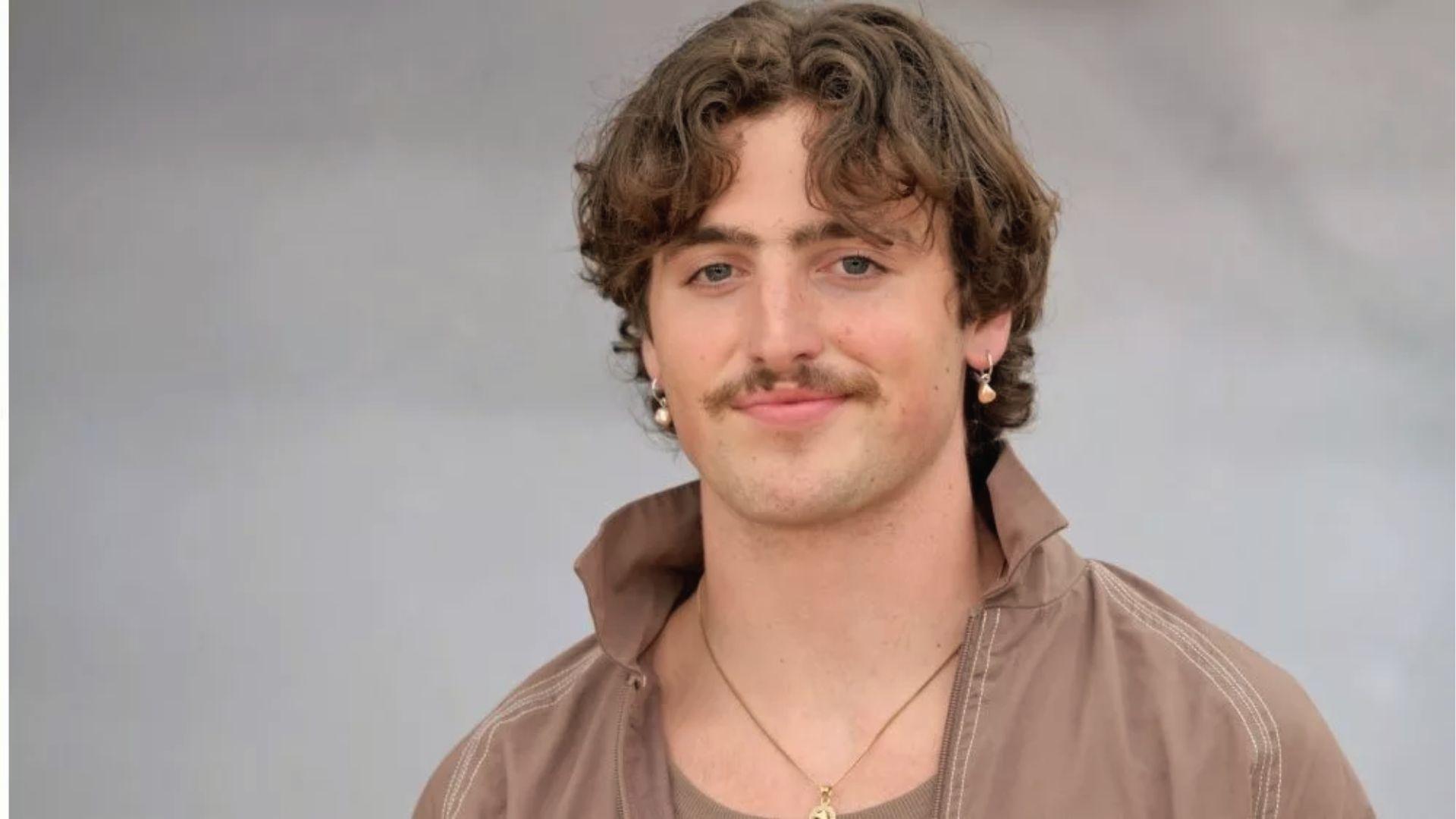 Benson Boone outdoor closeup with windswept wavy curls and signature mustache.