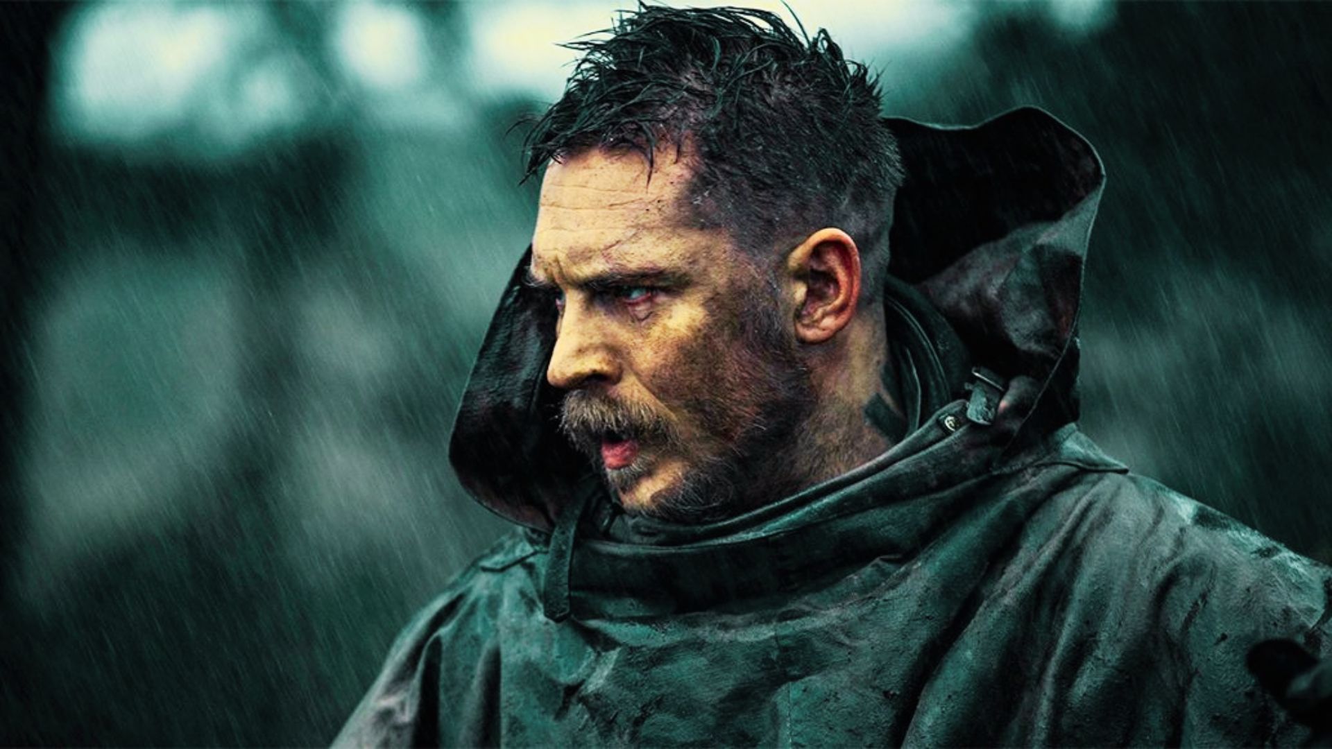 Tom Hardy in a dark raincoat during a rainy scene, showing a short buzzed military-style haircut with shaved sides.