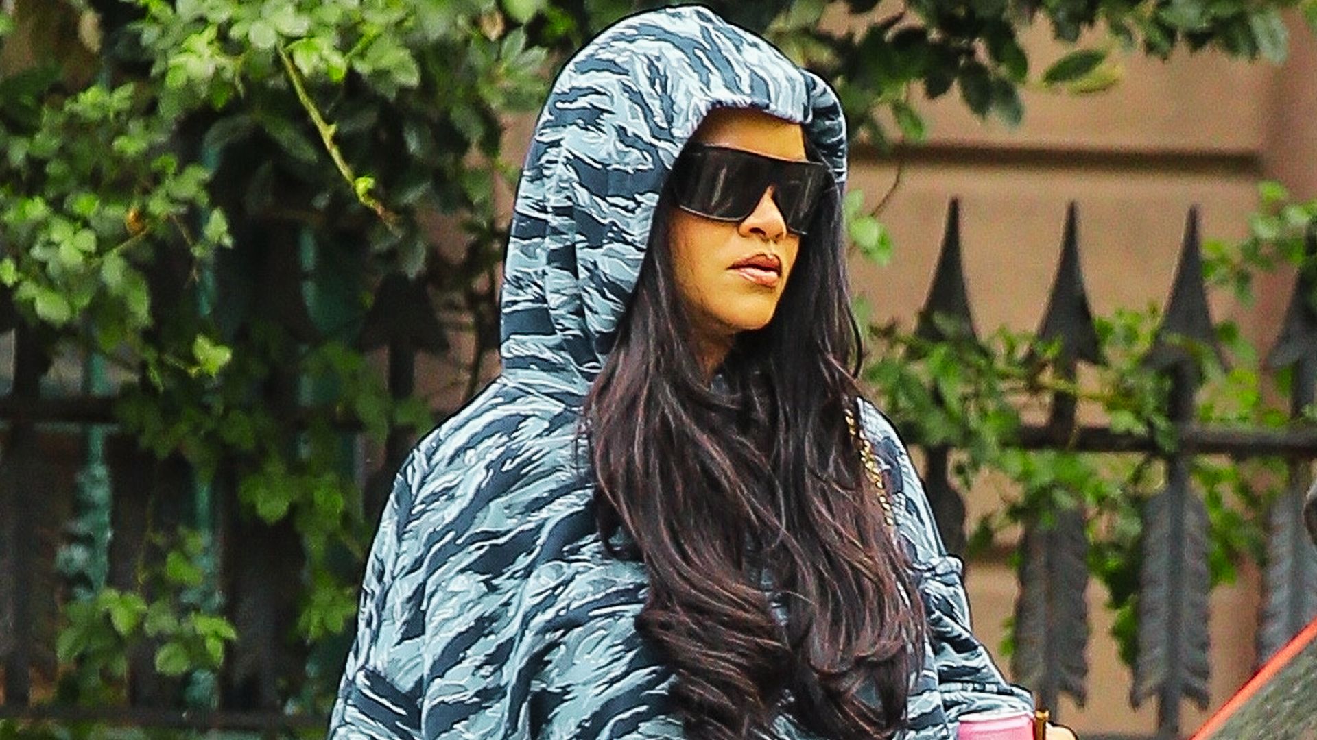 Rihanna steps out in an oversized camo-print puffer hoodie and shield sunglasses.
