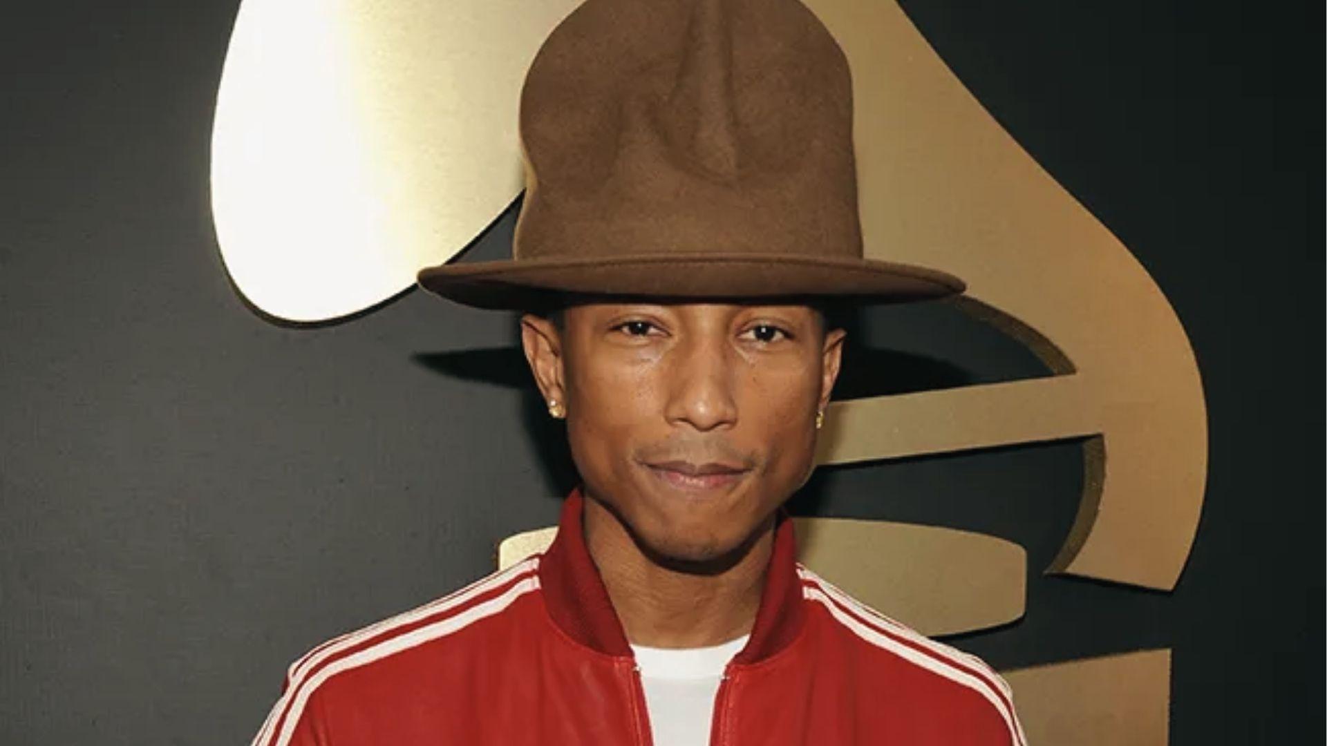 Pharrell Williams in red Adidas track jacket, oversized brown hat, Grammy backdrop