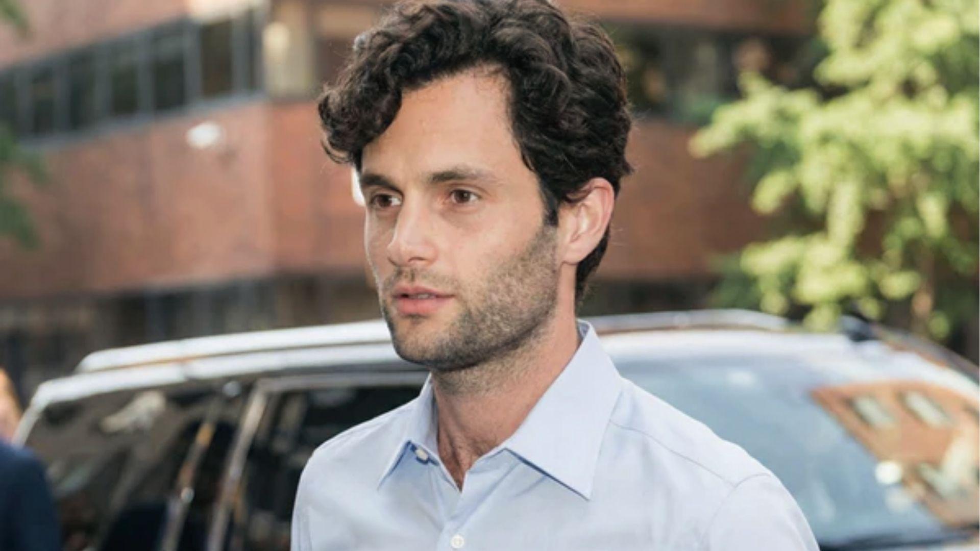 Penn Badgley features soft defined curls framing face wearing white shirt studio portrait.