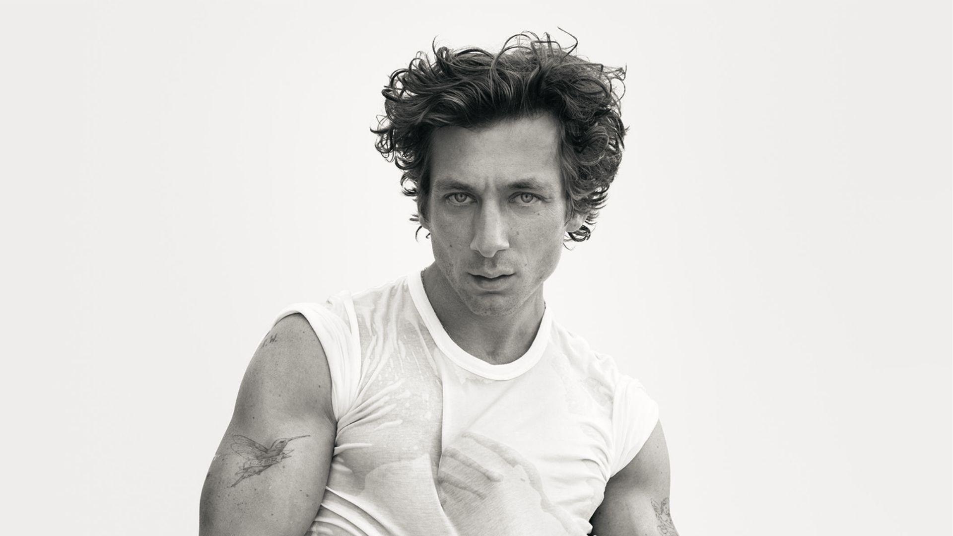 Jeremy Allen White displays wet-look textured dark curls with tousled fringe in black and white portrait