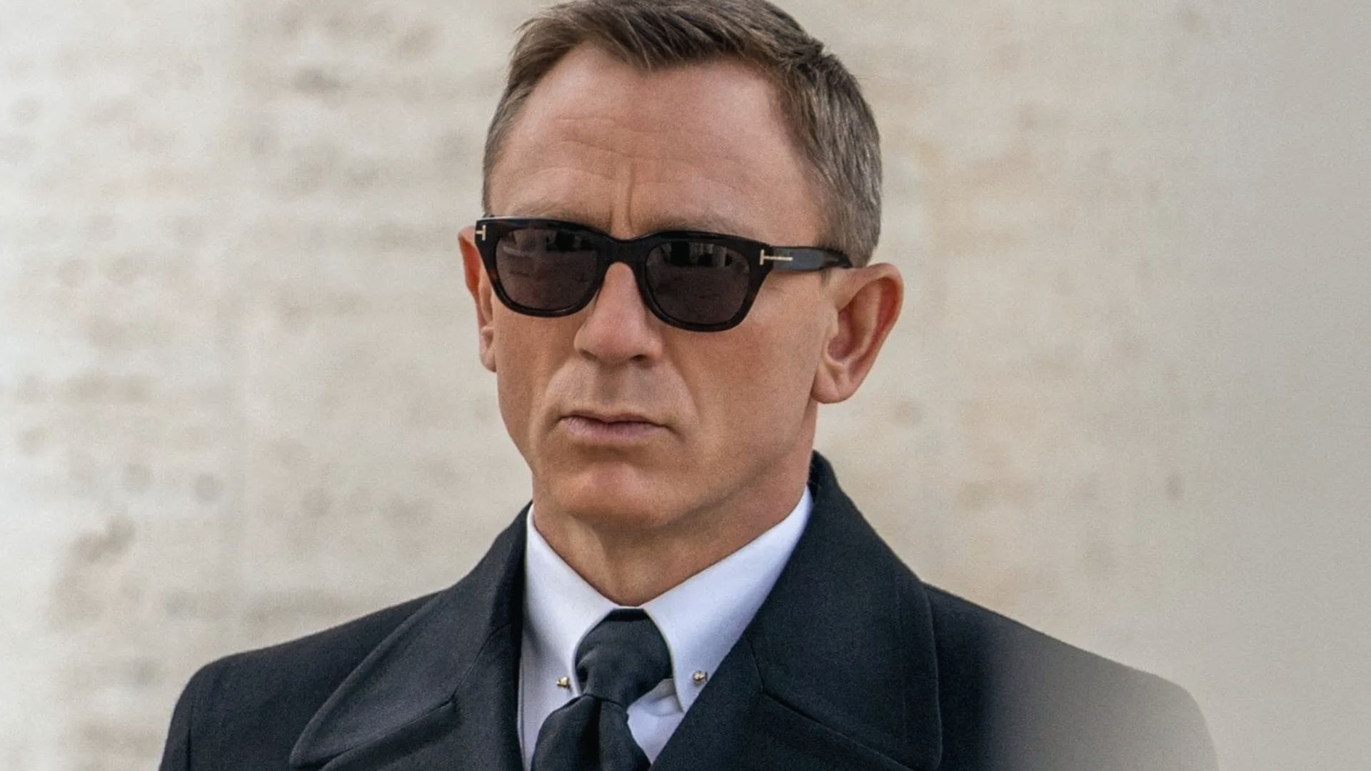 James Bond in a sleek suit and sunglasses, showcasing his iconic style and popular hairstyle.
