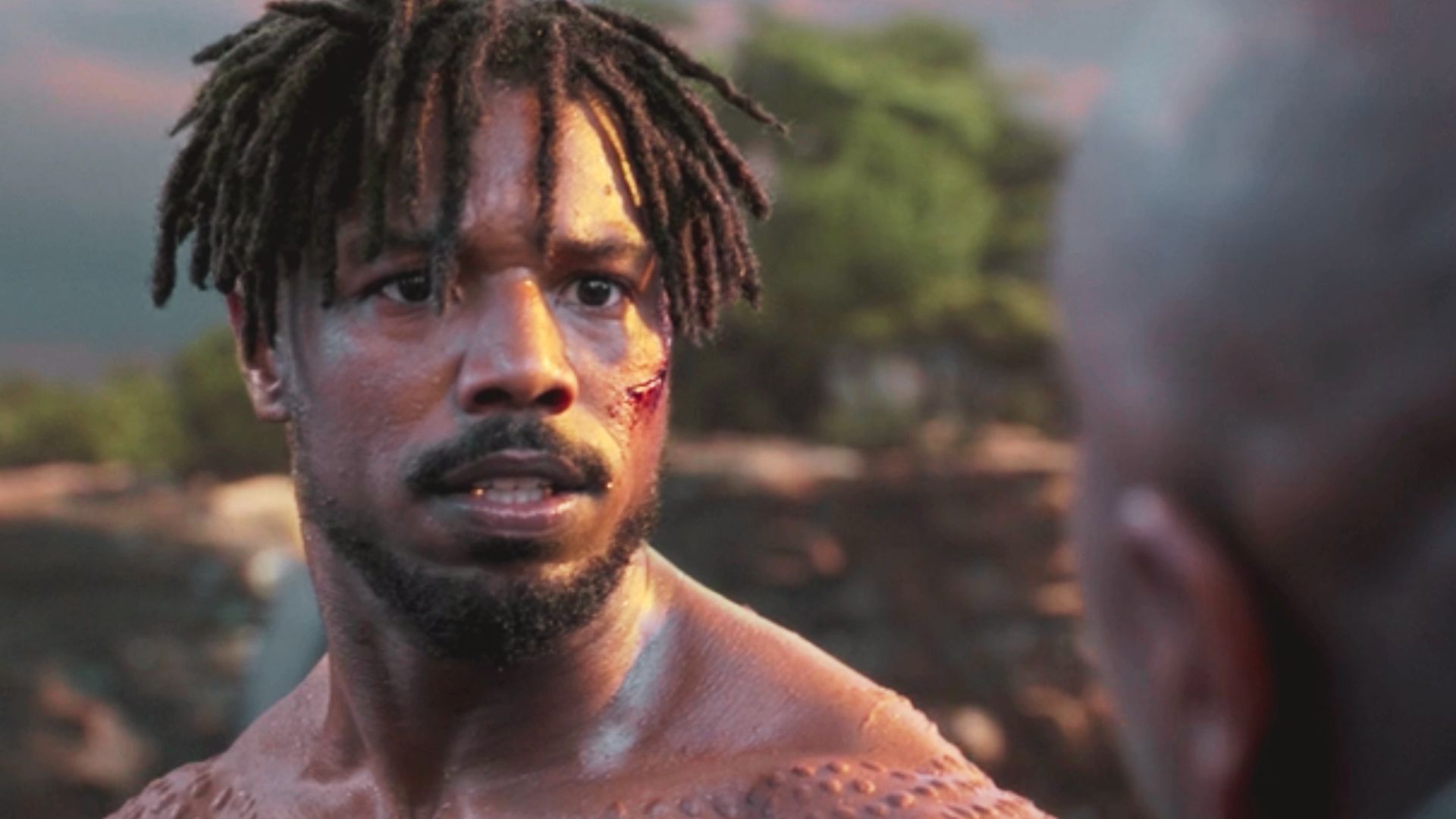 Michael B. Jordan as Killmonger with short locs styled forward over his forehead.