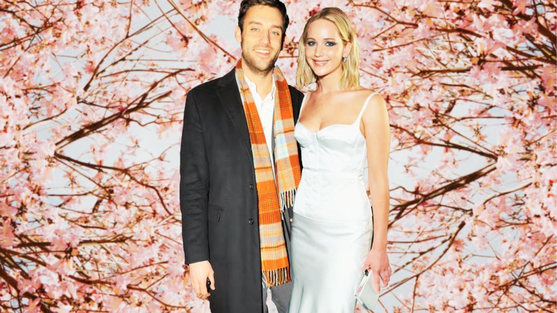 Couple poses smiling before cherry blossoms, woman in white dress, man in plaid scarf