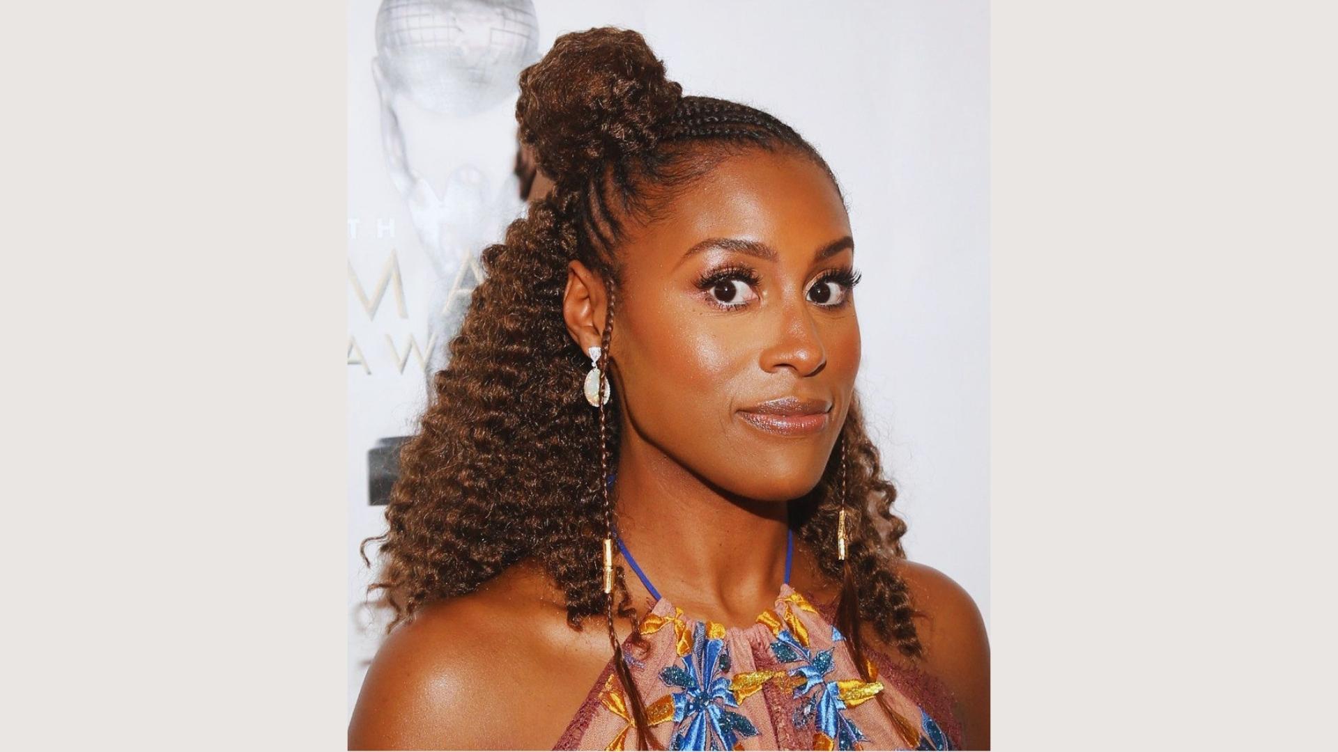 Issa Rae at the NAACP Image Awards with a half-up braided bun, curly extensions, and gold hair cuffs.