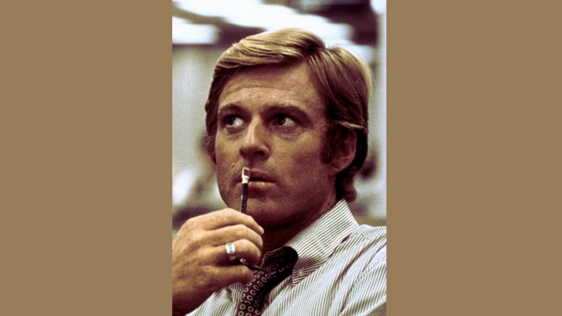 "A man with a relaxed expression, holding an object in his mouth, standing outdoors."