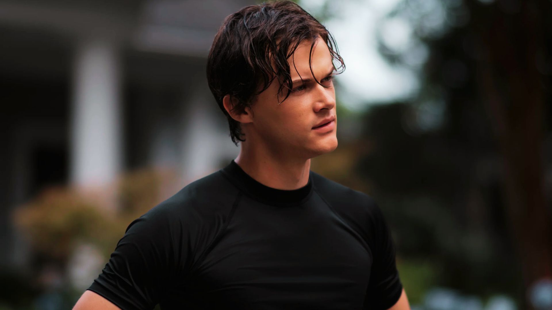 Conrad with wet hair wears a fitted black athletic shirt outdoors.