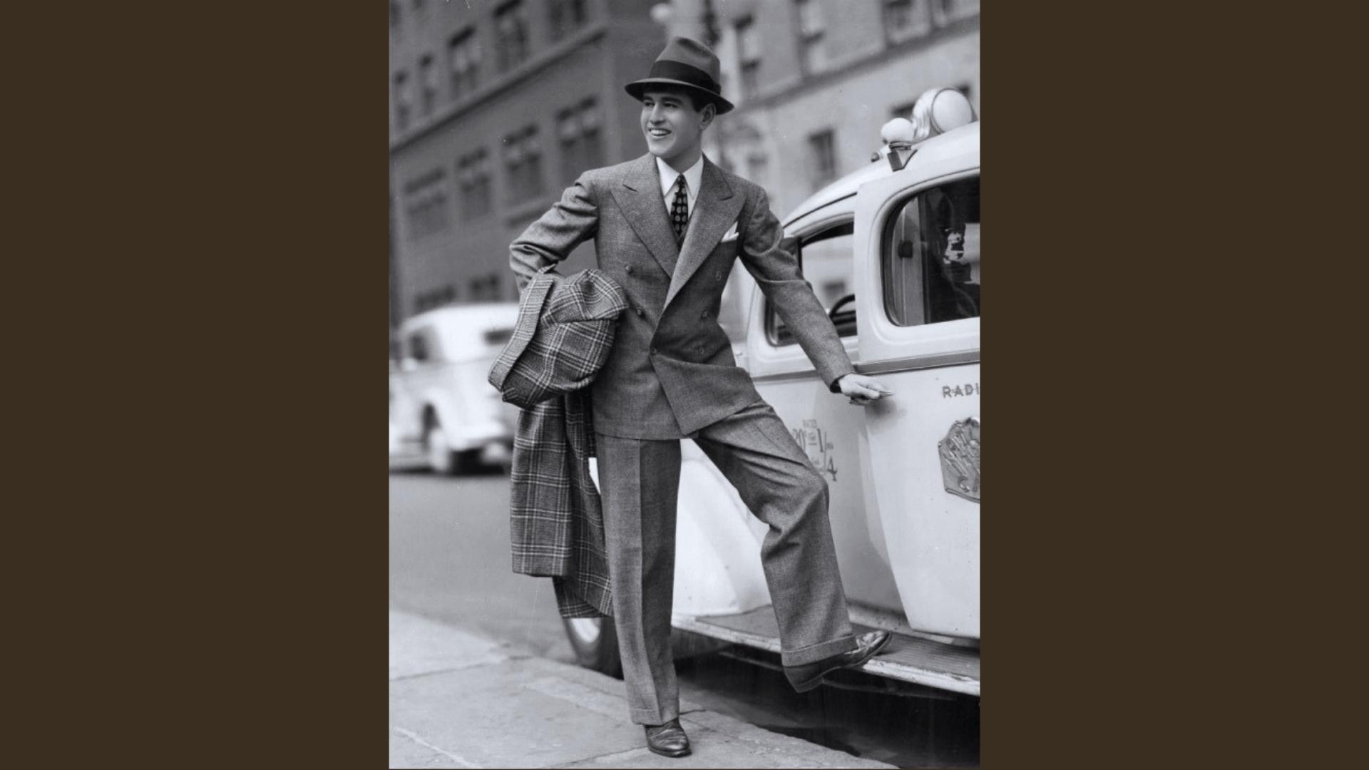 Vintage black-and-white photo of man in double-breasted suit, fedora, and overcoat stepping out of taxi.