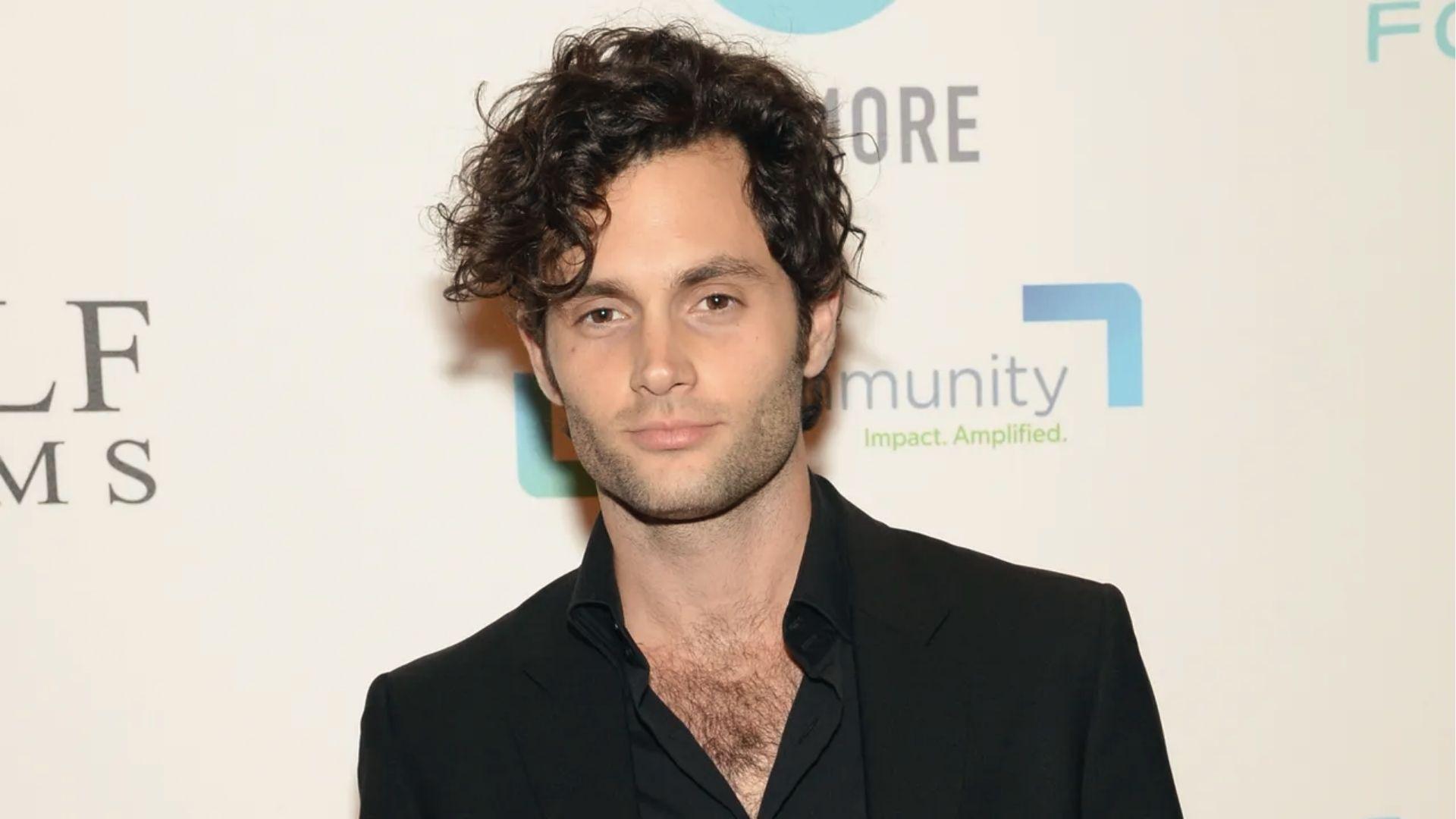 Penn Badgley rocks messy medium-length curls with black suit at a red carpet event.