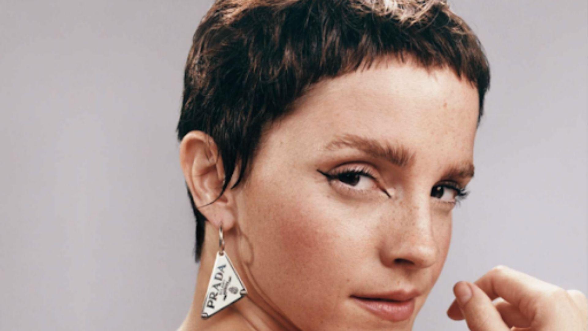 Emma Watson poses with edgy choppy pixie cut and bold winged liner, Prada earring.