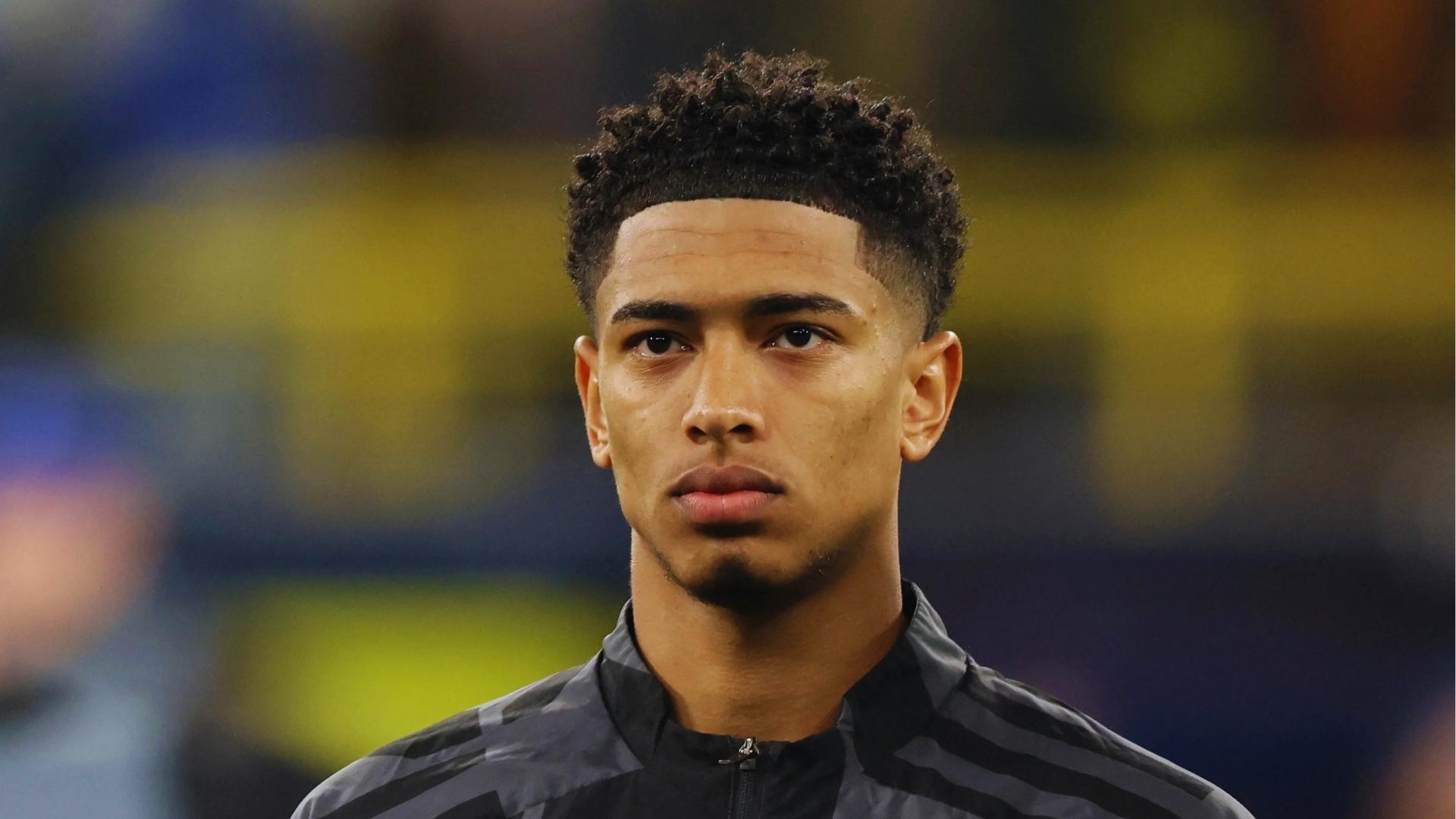 Jude Bellingham on the pitch with a tight curly afro, defined shape-up, and tapered sides for a sporty look.