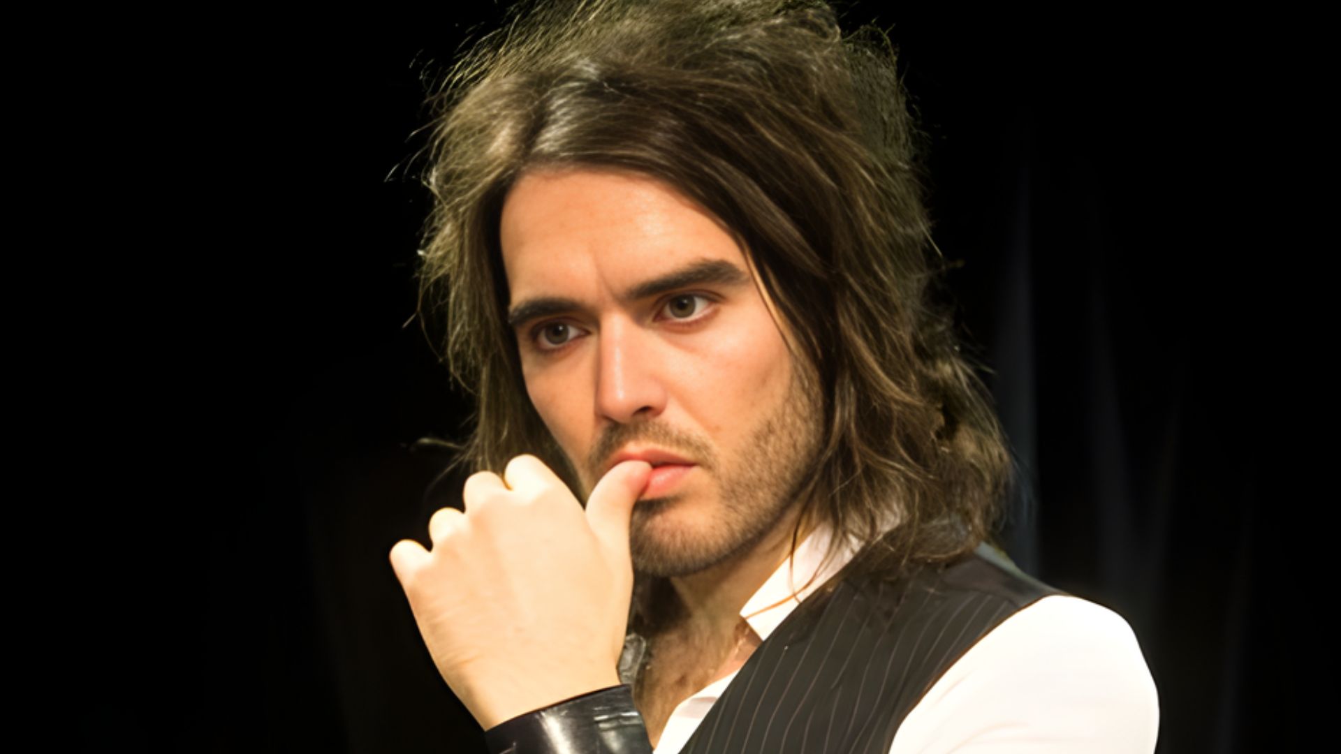 A close-up of Russell Brand with messy side-swept short hair, highlighting his unique and trendy hairstyle.
