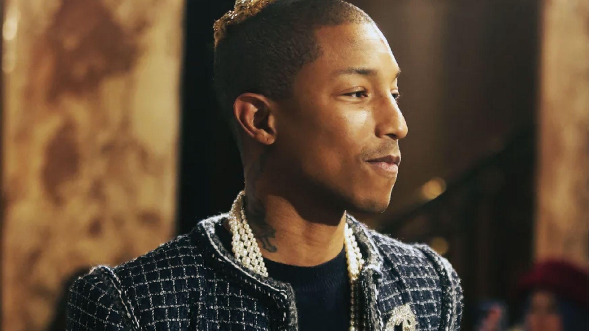 Pharrell Williams profile in black Chanel tweed jacket, layered pearl necklaces, gold grill