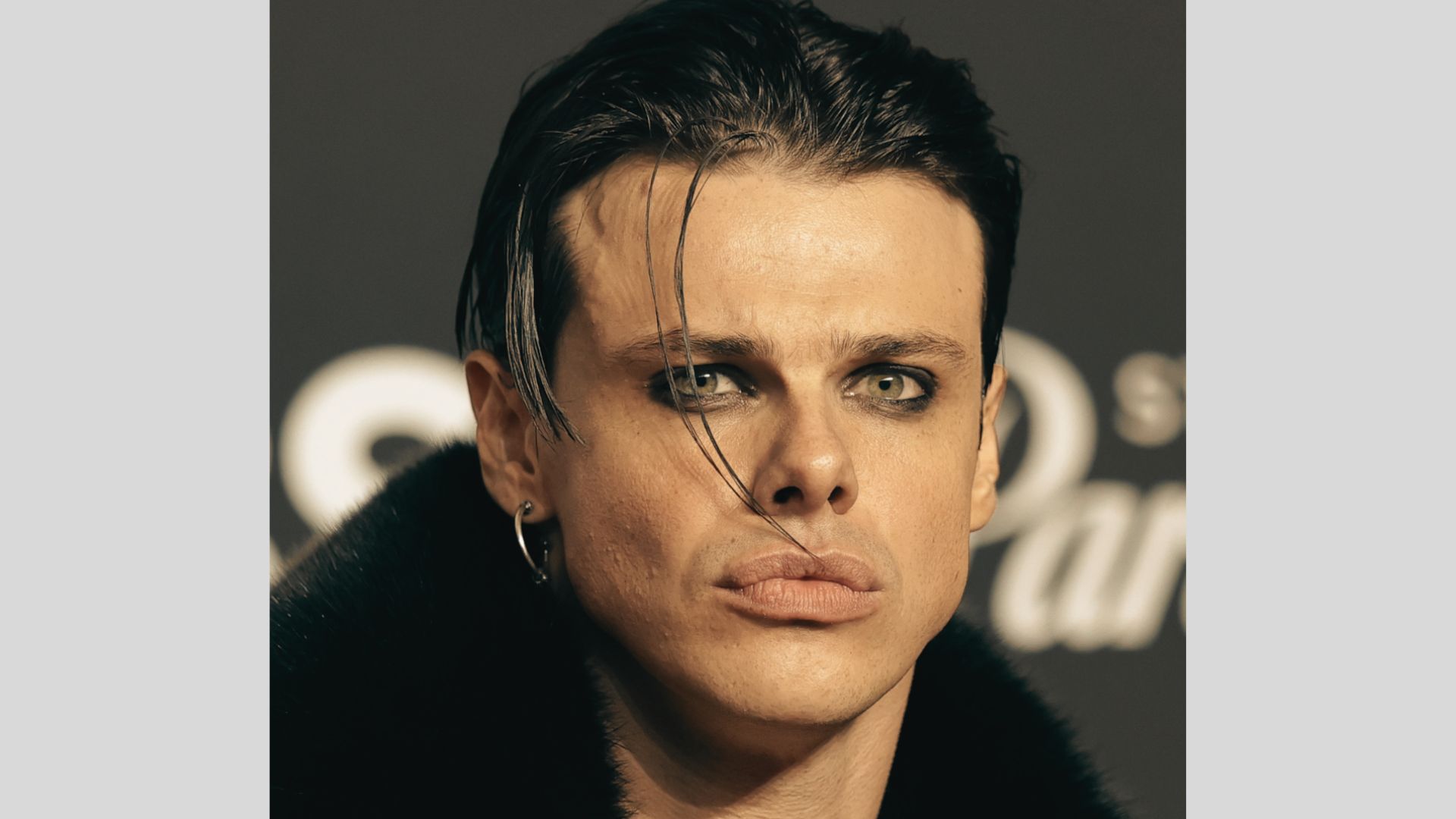 Yungblud with a slick, grown-out mullet and single strands hanging over the forehead.