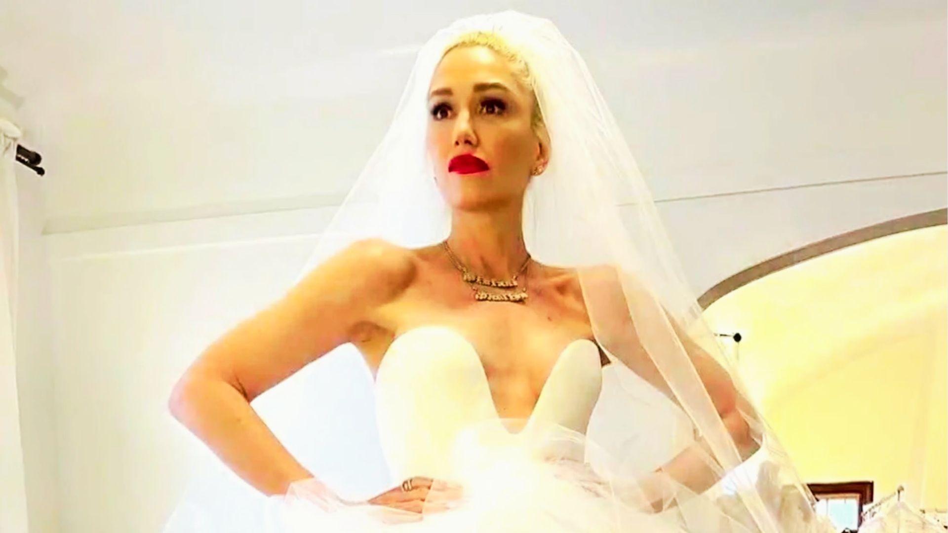 Bride in plunging strapless gown and veil with red lipstick stands confidently with hands on hips