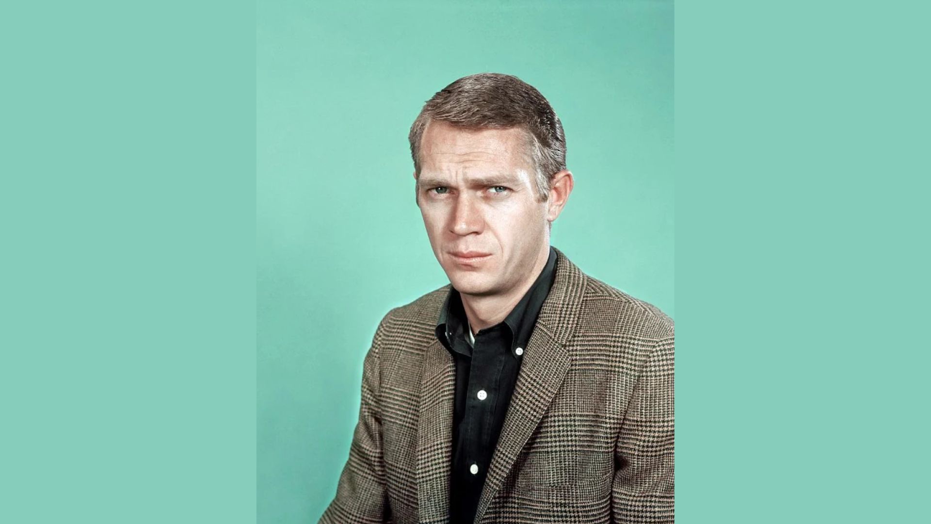 "A man in a suit and tie gazes directly at the camera with a confident expression."