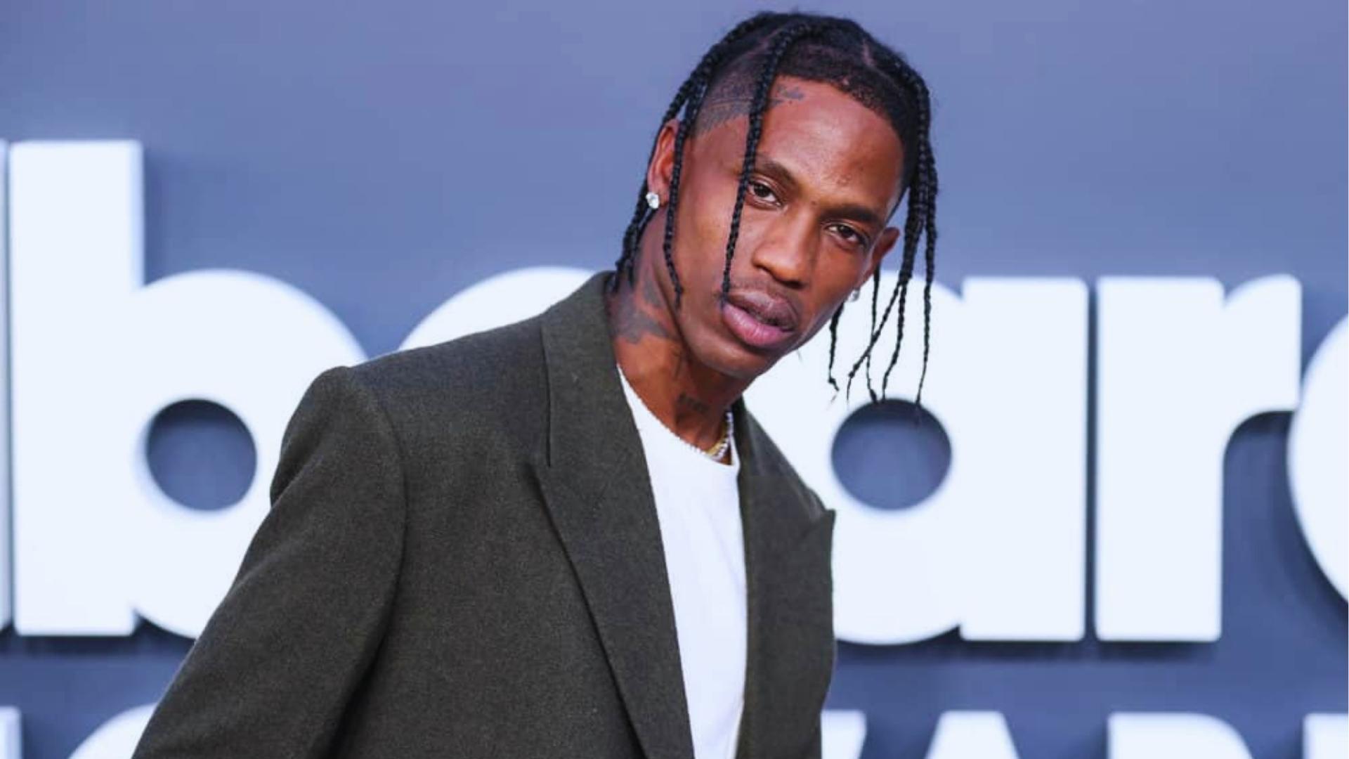 Travis Scott at an awards show with long thin braids and shaved sides, paired with an olive blazer.