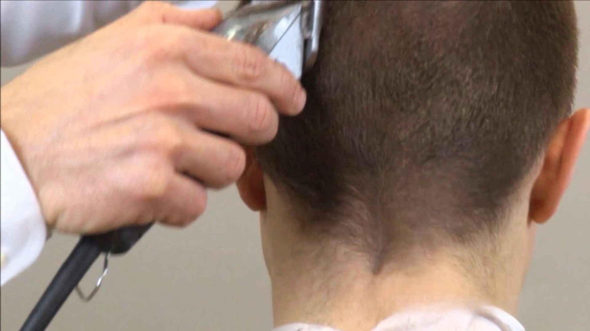 A barber styles a man's hair, illustrating the process of Telling for the James Bond haircut.