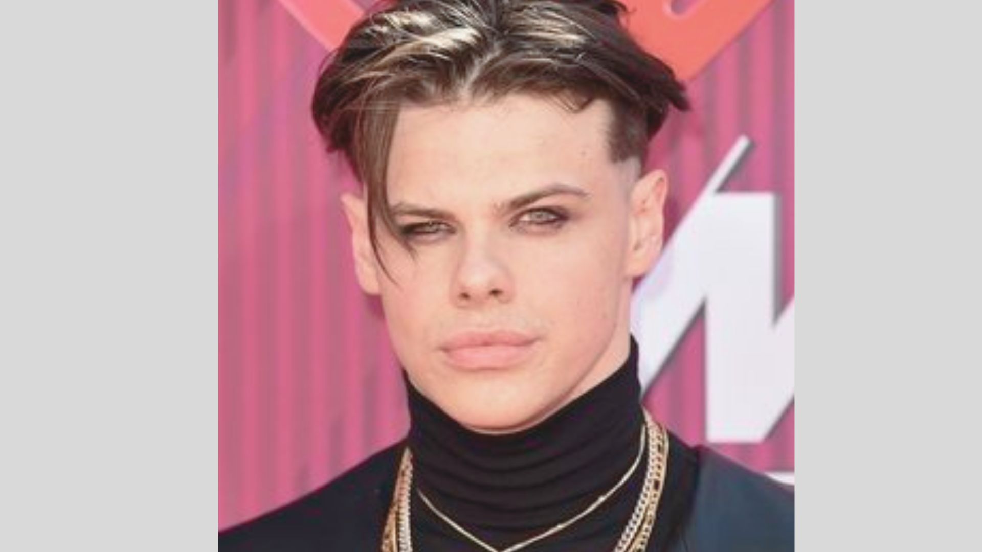Yungblud sports his signature disconnected undercut with long, textured top and blonde highlights.