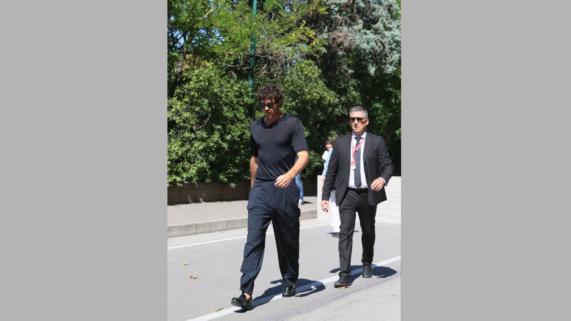 Two men in suits walking side by side down a city street, engaged in conversation.