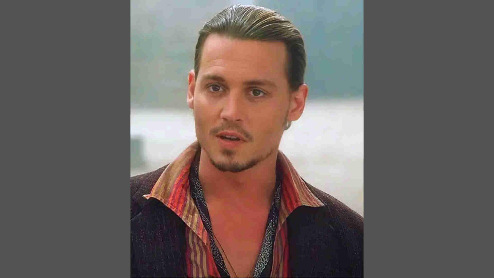 Johnny Depp sporting slicked-back short hair and goatee in striped shirt under dark blazer outdoors.