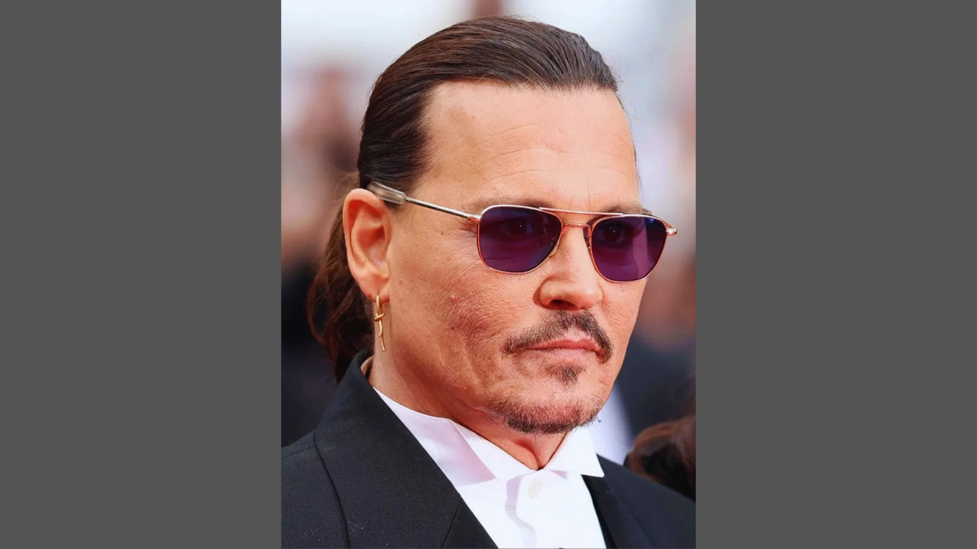 Bedhead low ponytail on Johnny with loose strands, natural texture, relaxed style, and close-up face portrait