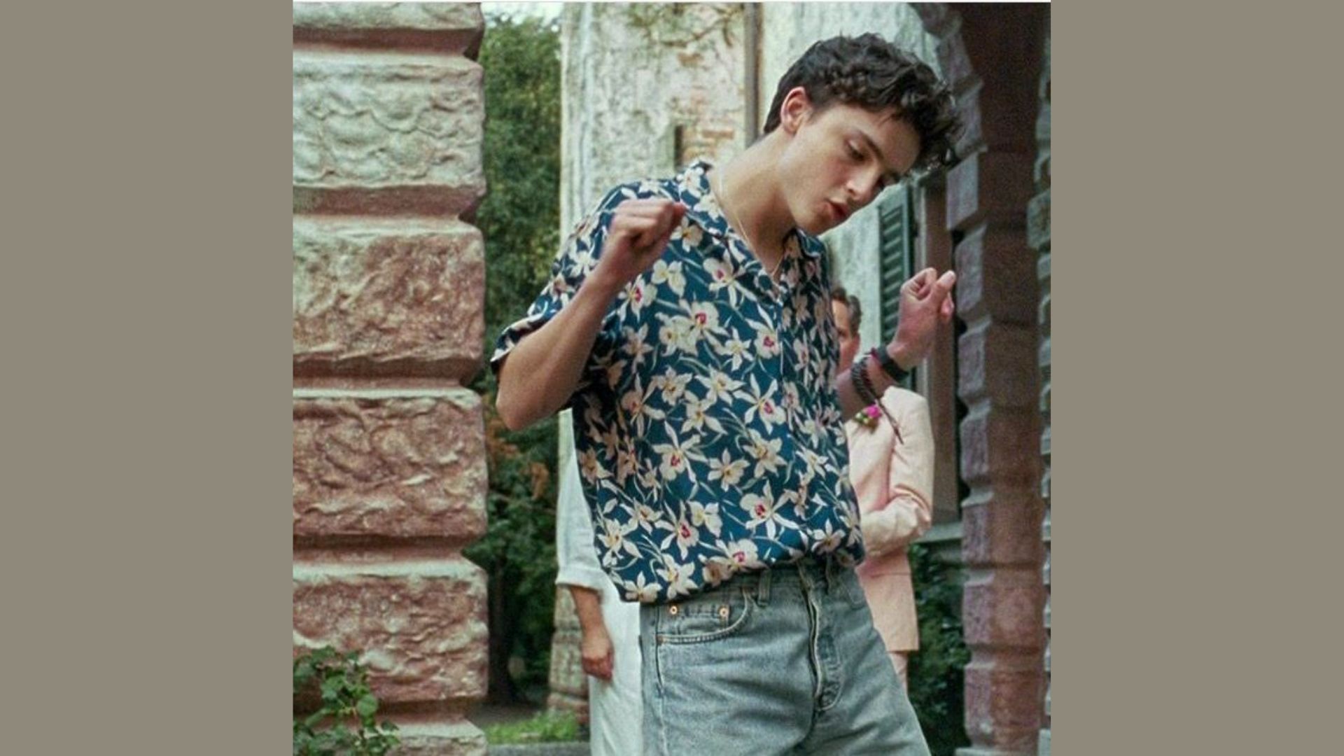 A man wearing a floral shirt and jeans is joyfully dancing, showcasing lively movements and a cheerful expression."